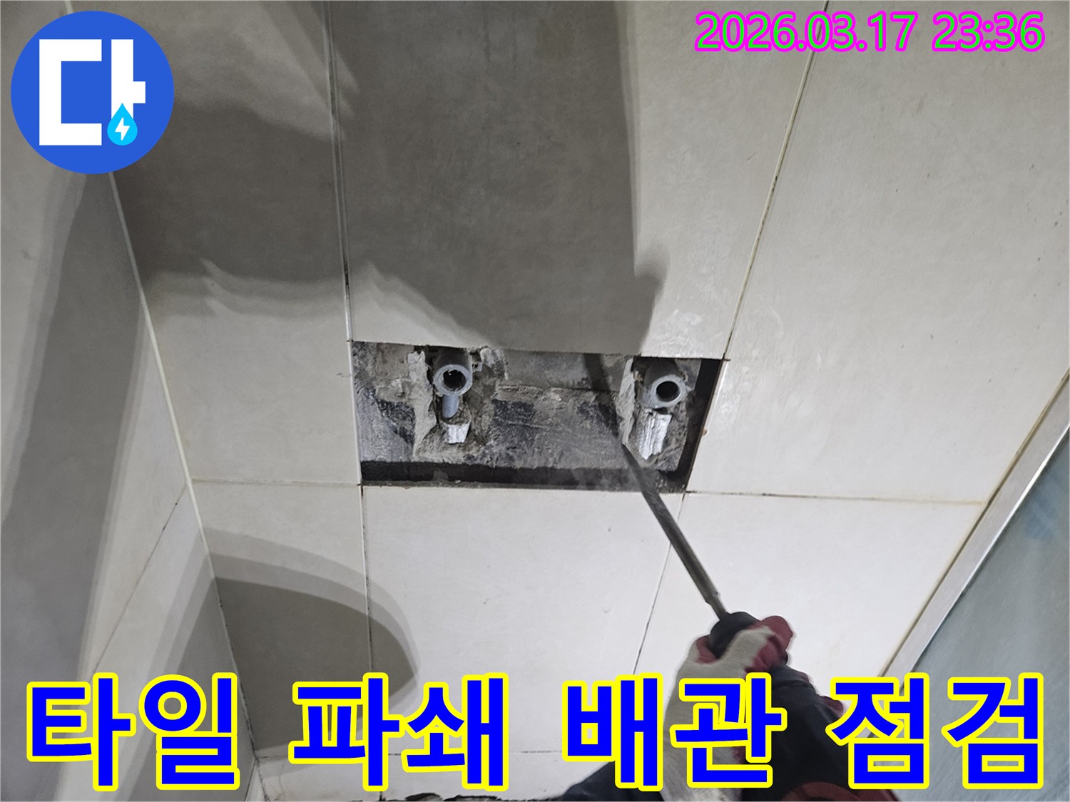 누수 탐지 전문가가-욕실 벽면 타일을-조심스럽게 파쇄하여-배관 점검을-시작하는 모습