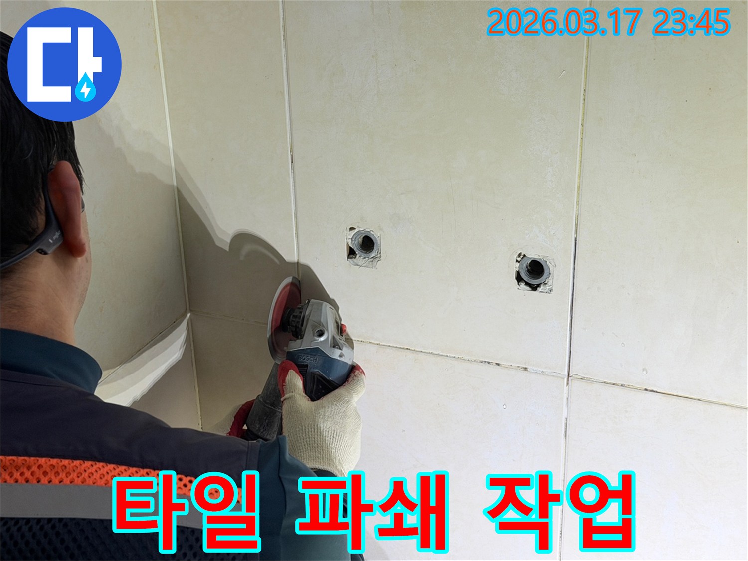 누수된 배관에-접근하기 위해-전문가가-타일 벽면을-그라인더로-파쇄하는-작업을-진행하고-있습니다