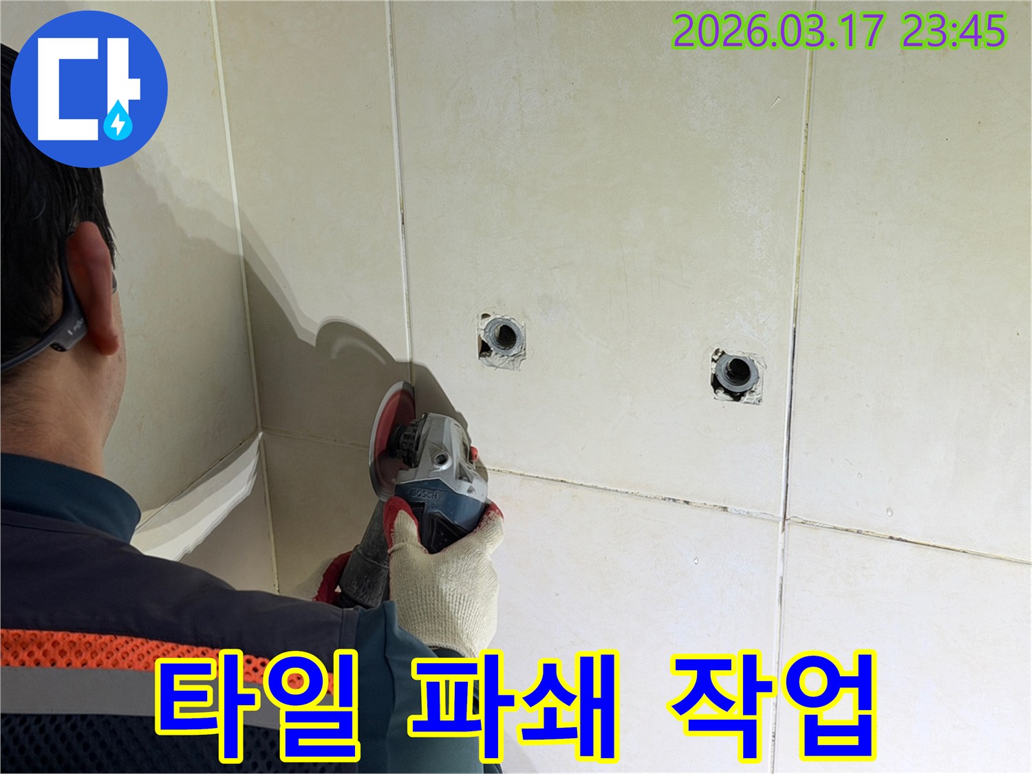 누수된 배관에-접근하기 위해-전문가가-타일 벽면을-그라인더로-파쇄하는-작업을-진행하고-있습니다