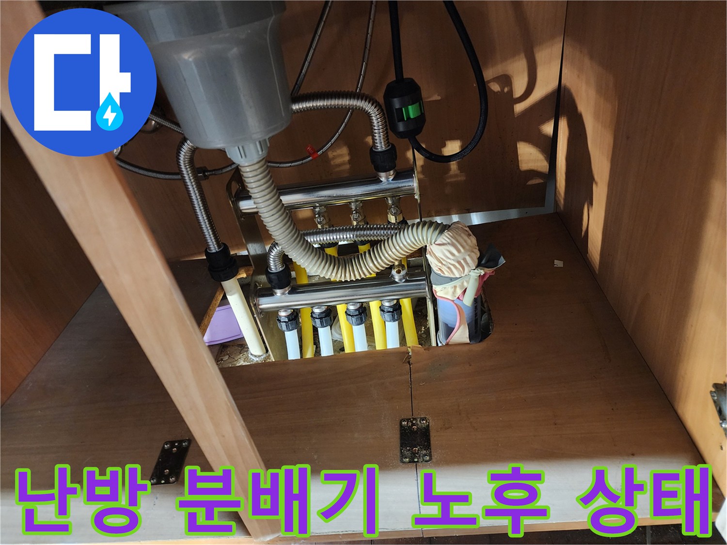 싱크대 하부장 내부-노출된 난방 분배기와 연결된 유연한 배관들