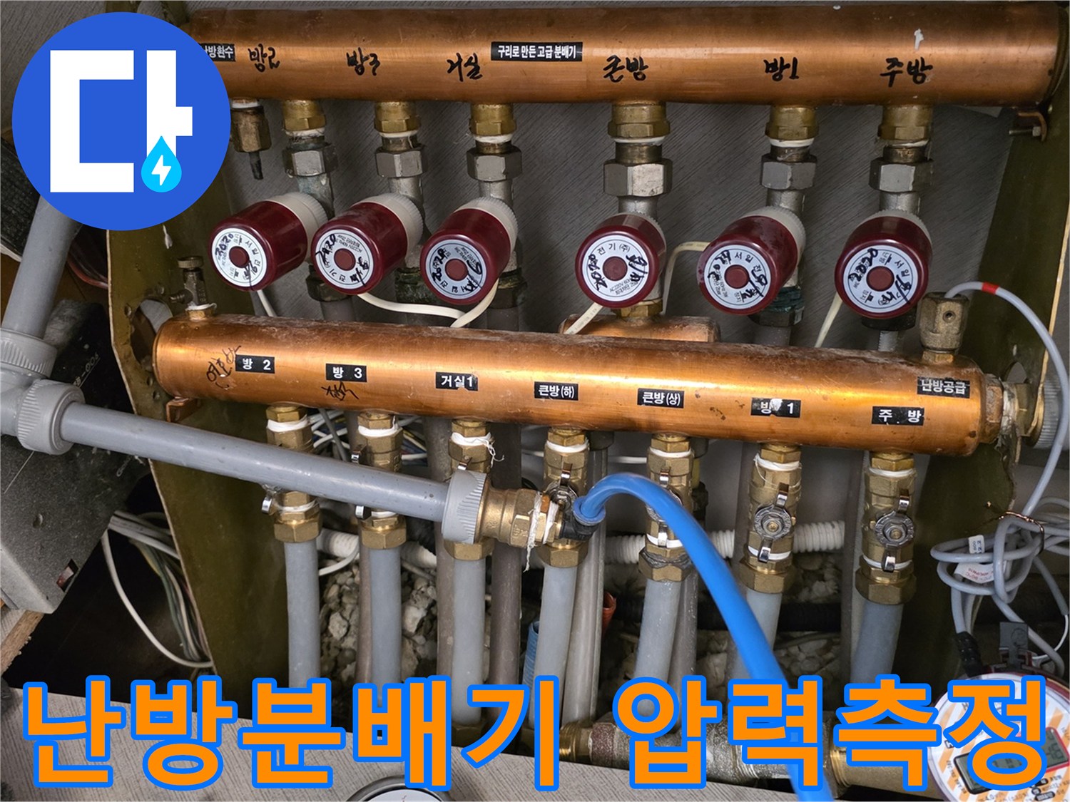 난방 분배기에 연결된 파란색 호스와 압력 측정 장비