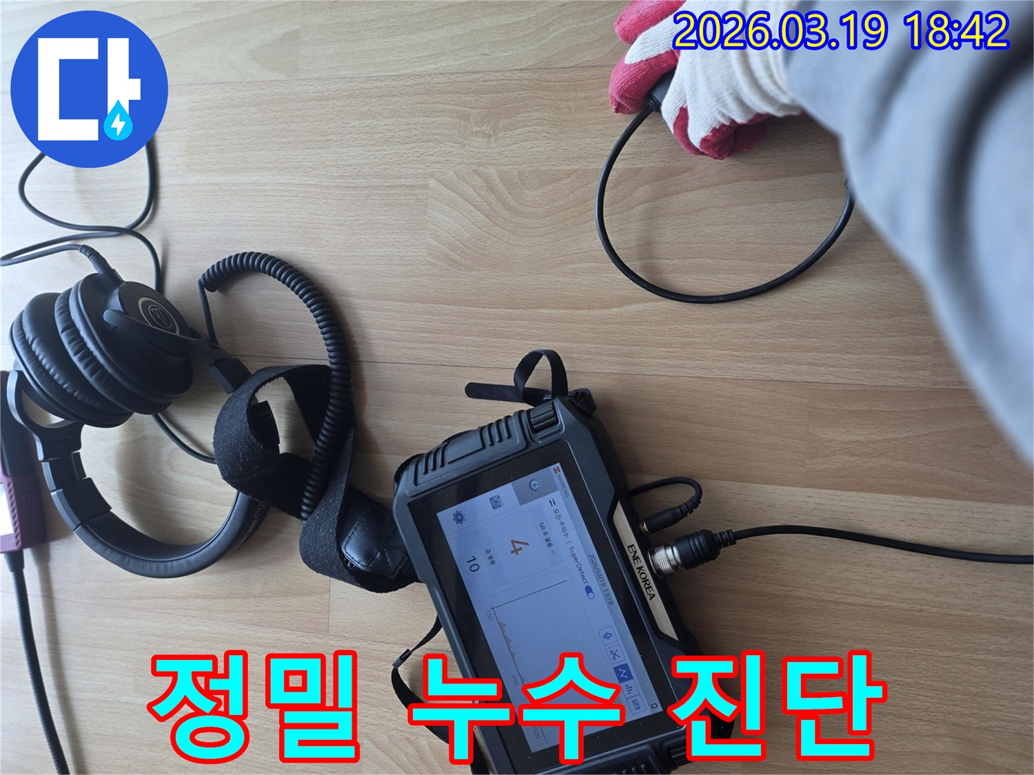 숙련된 엔지니어가-누수 탐지 장비를 활용하여-바닥에서 발생하는-미세한 누수 소리를-집중적으로 듣고 분석하는 장면입니다
