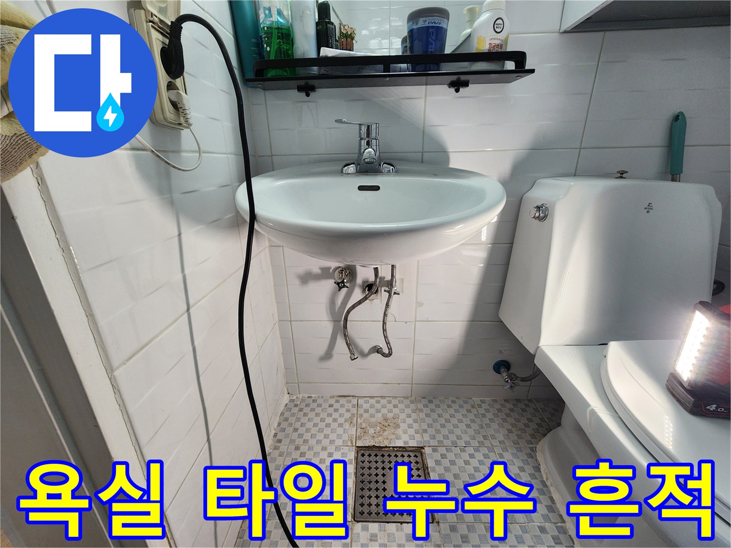 세면대 하단부의 젖은 타일과 배수구 상태