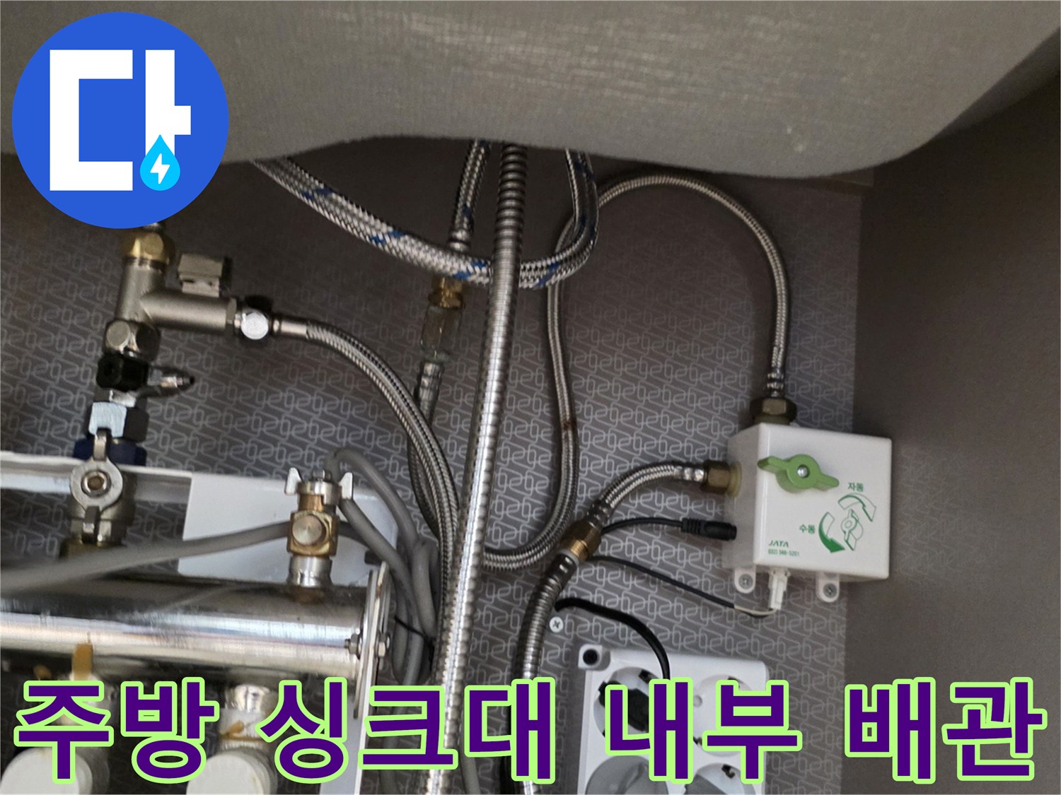 싱크대 하부장 내부에 설치된 금속 분배기와 급수 호스들