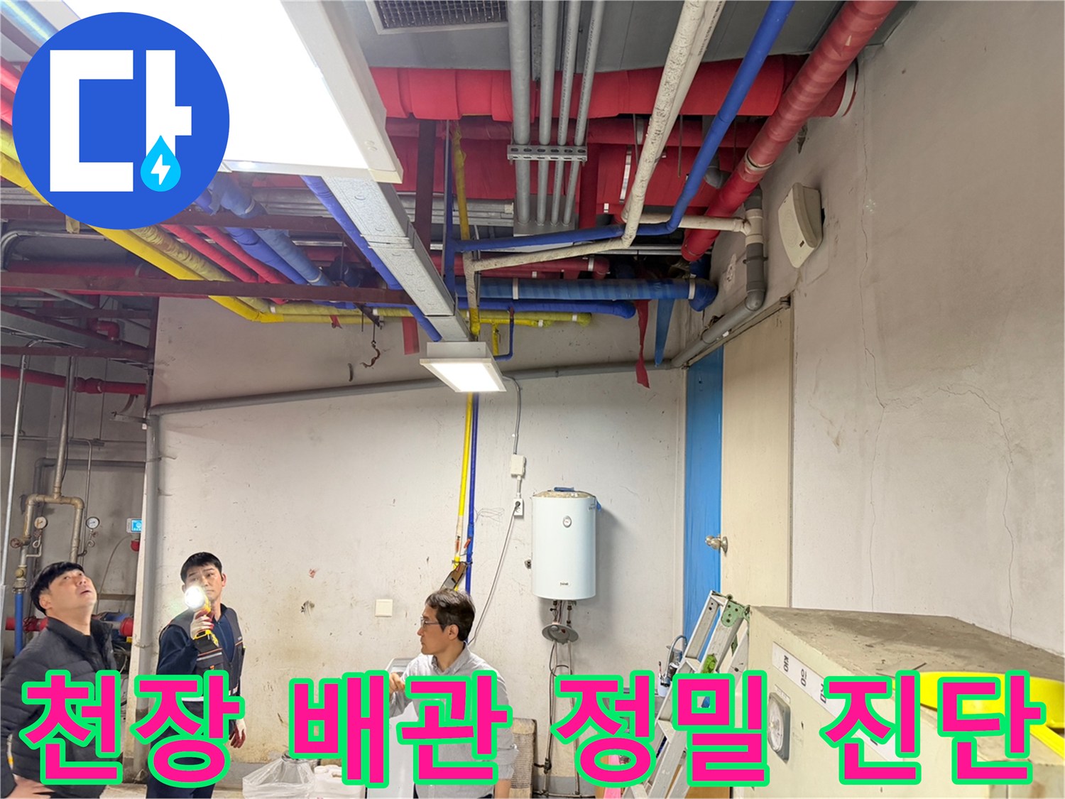 엔지니어가 손전등을 사용하여 천장의 다양한 색상 배관들을 조사하고 있습니다.