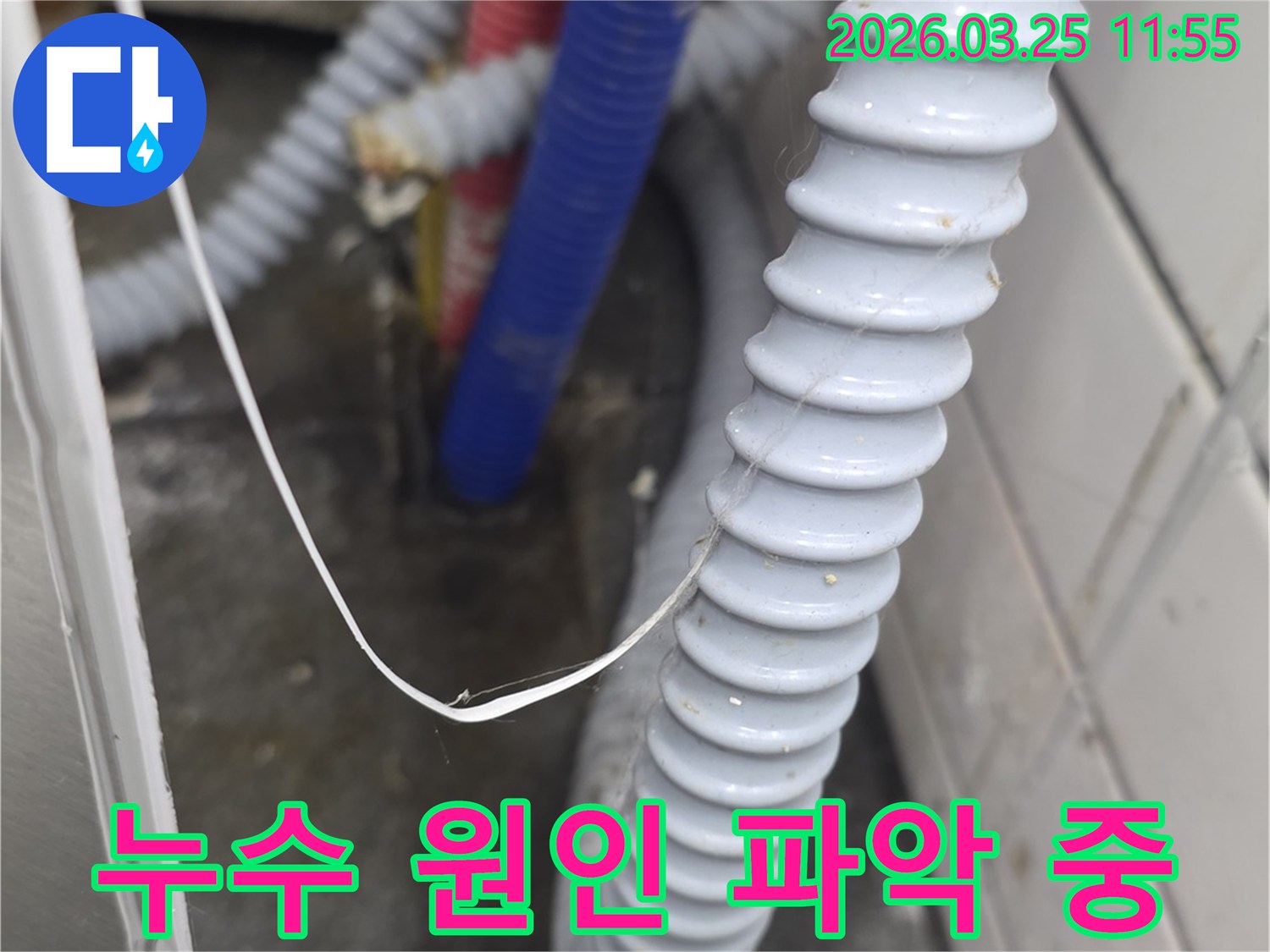 복잡하게 얽힌 배관과-주름진 호스 주변에서-누수 엔지니어가-물기나 습기 흔적을 통해-누수 원인을 파악하는 모습