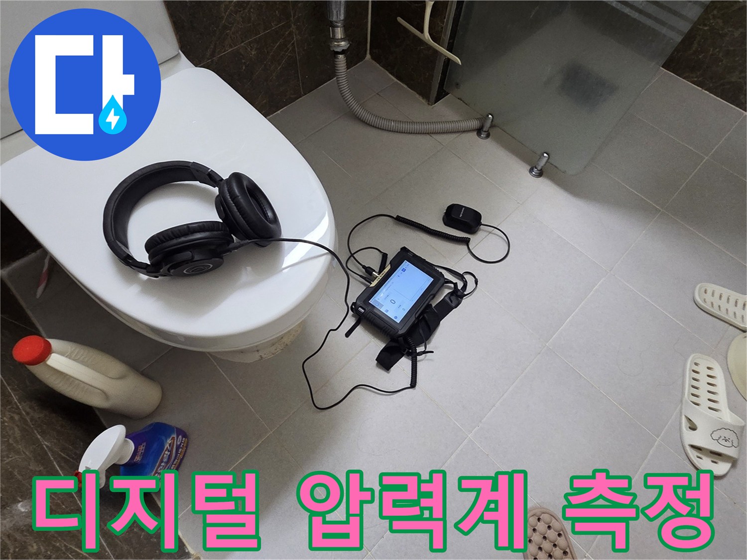 변기 옆에 놓인 청음 헤드셋과 디지털 압력 장치-누수 탐지 진행 중
