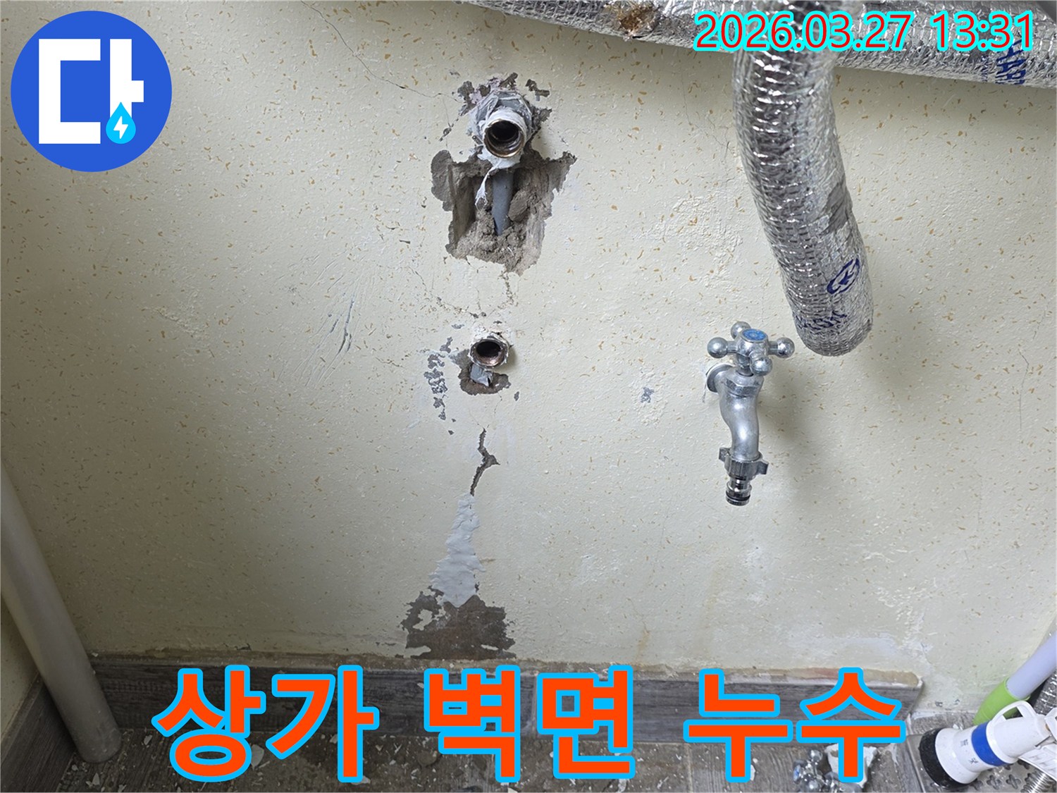 상가 건물 벽면에서 발견된 누수-흔적과 주변 배관-시설물을 함께 보여줍니다.