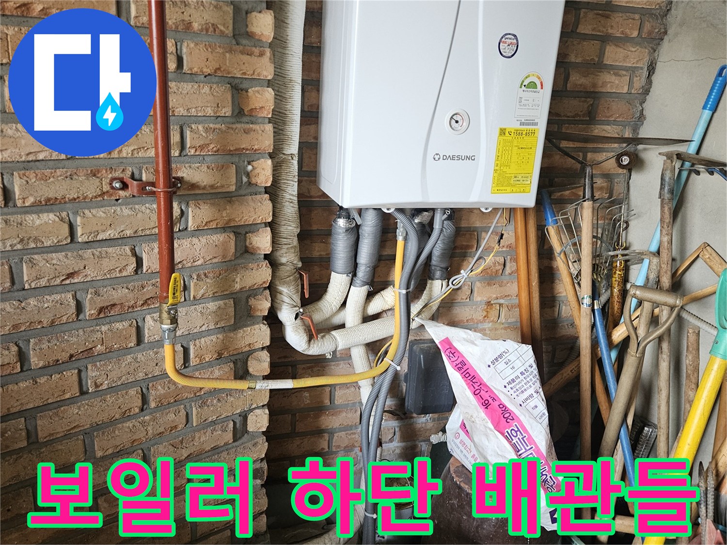 벽돌 구조물 위에 설치된 보일러와 연결 배관의 근접 촬영입니다.