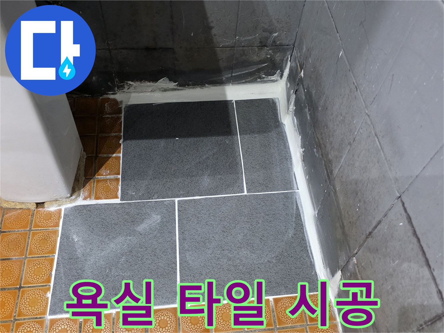 새로 부착된 어두운 회색 타일과 기존 노란 타일의 경계면
