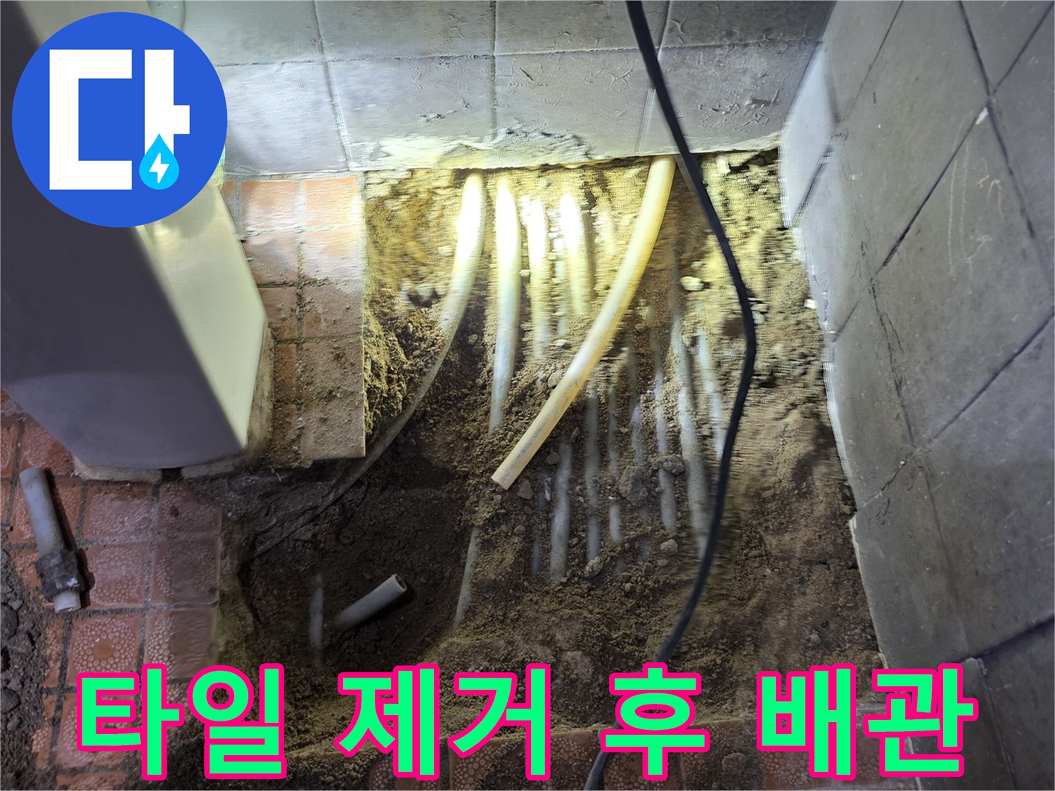 제거된 타일 옆으로 드러난 젖은 흙과 노출된 수도 관로