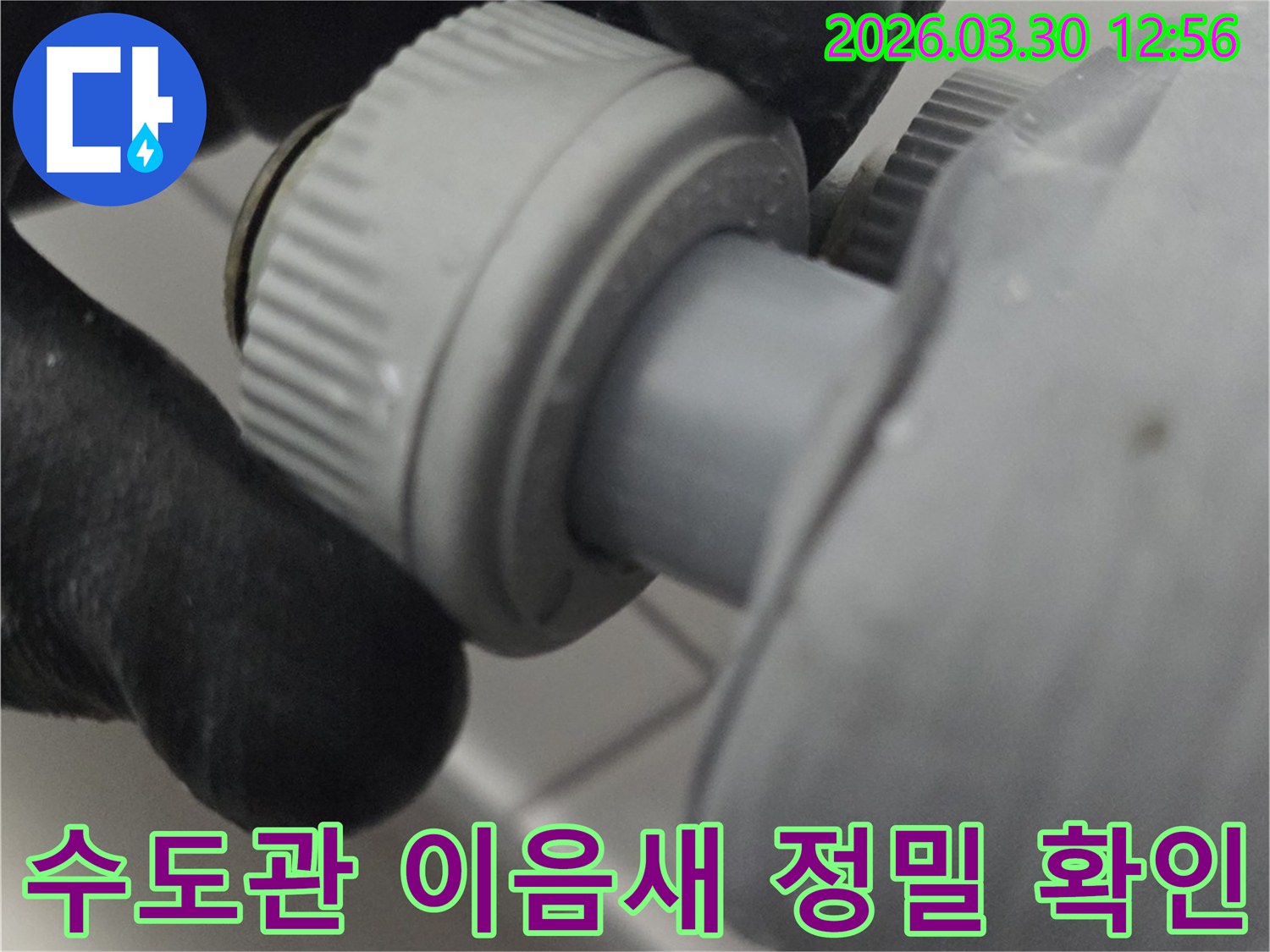 검은 장갑을 낀 손이 수도 배관의 연결 부위를 꼼꼼하게 점검하고 있는 모습