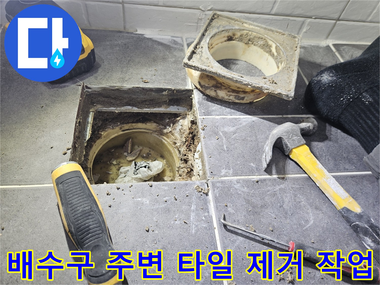 망치와 도구를 사용하여 배수구 주변 타일을 걷어낸 모습입니다.