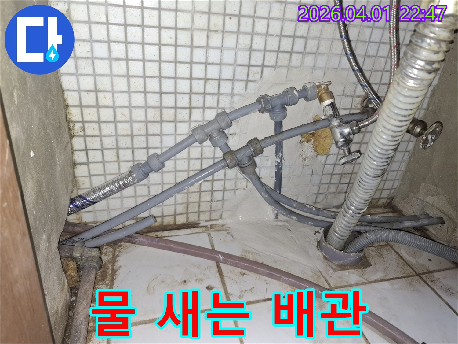 복잡한 배관 연결부에서-물이 새어 나와-바닥에 고여있는-누수 상황을-생생하게 보여주는-사진입니다.