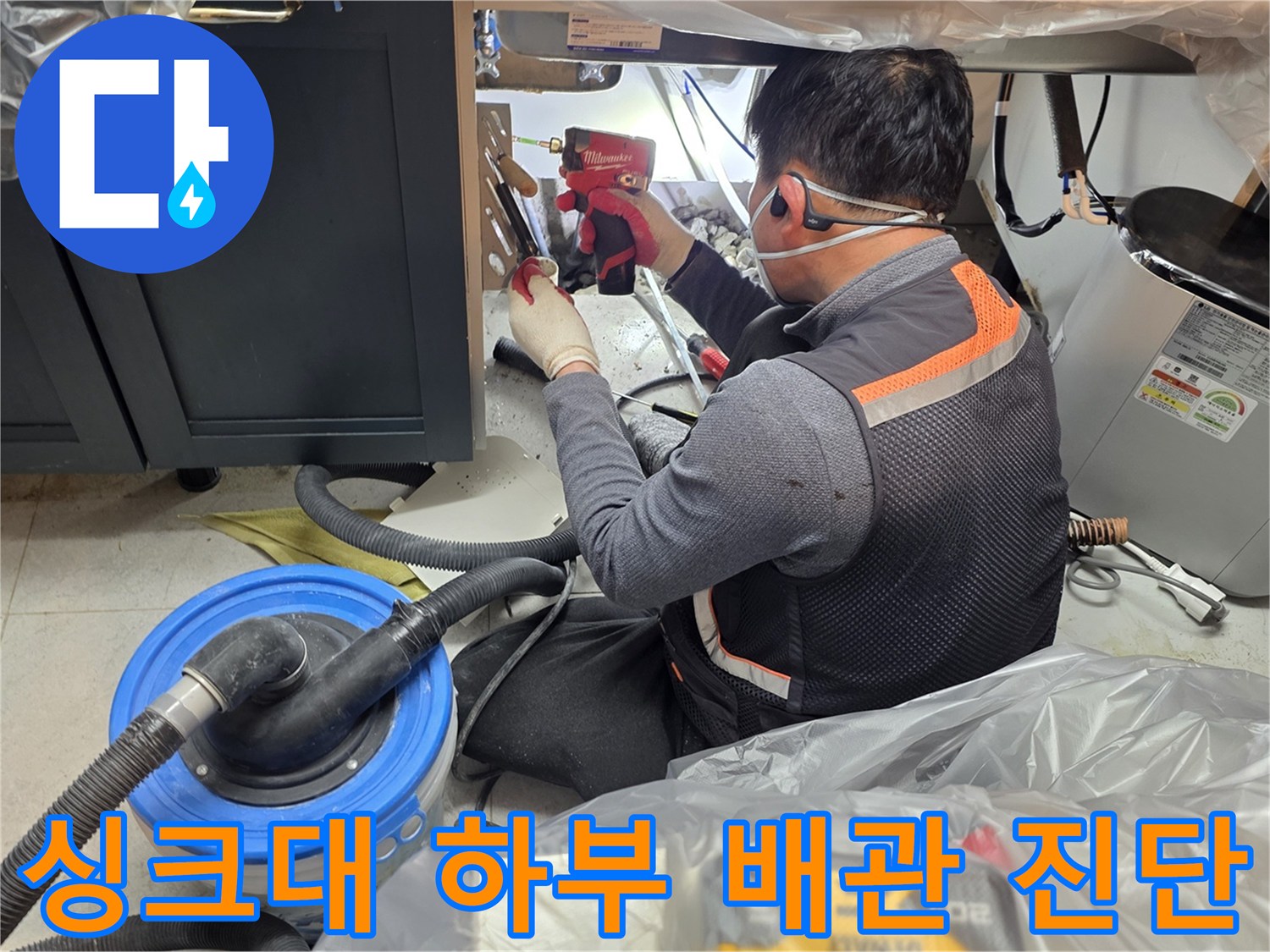 싱크대 아래쪽 좁은 공간에서 배관을 점검하는 작업자