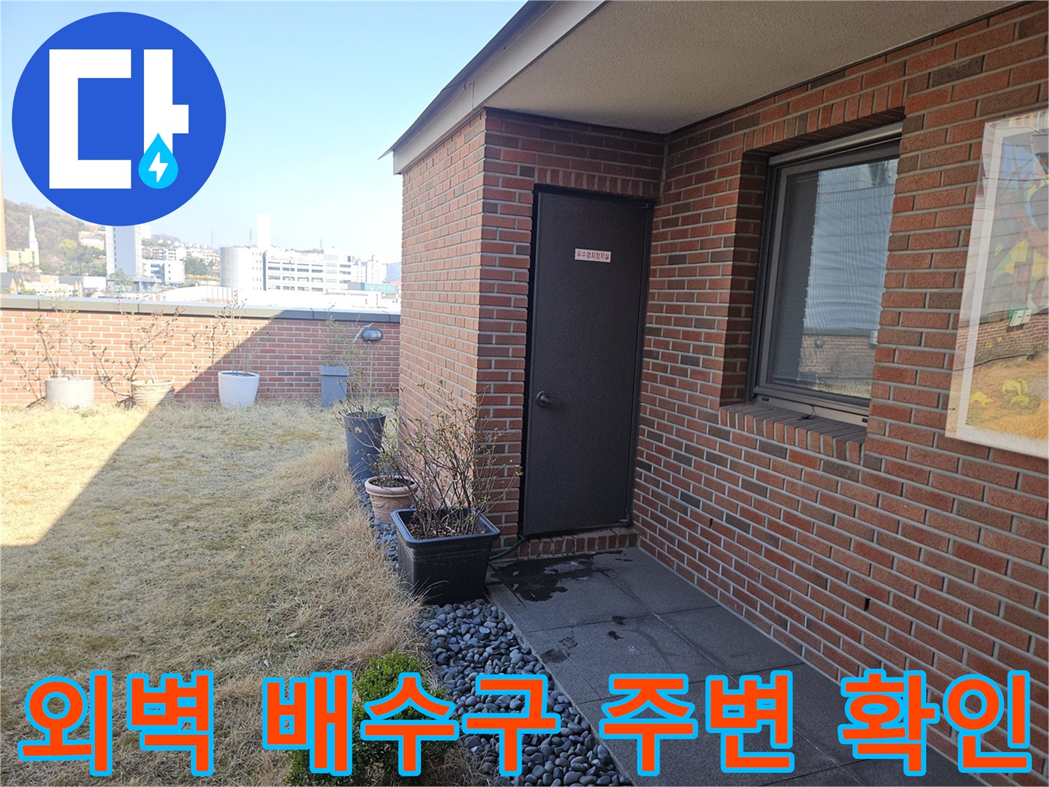 건물 벽돌 구조물과 배수구가 만나는 지점을 촬영한 사진입니다.