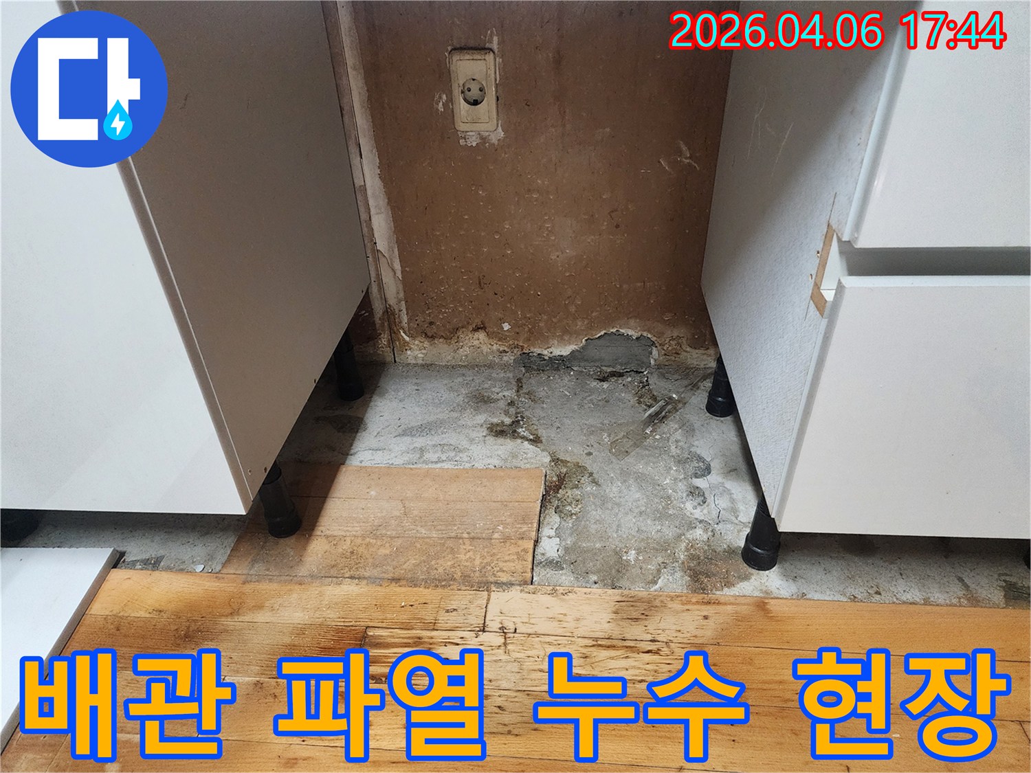 싱크대 아래 바닥과 벽면에 물이 흥건하고-마루가 심하게 손상된-배관 파열 의심 현장