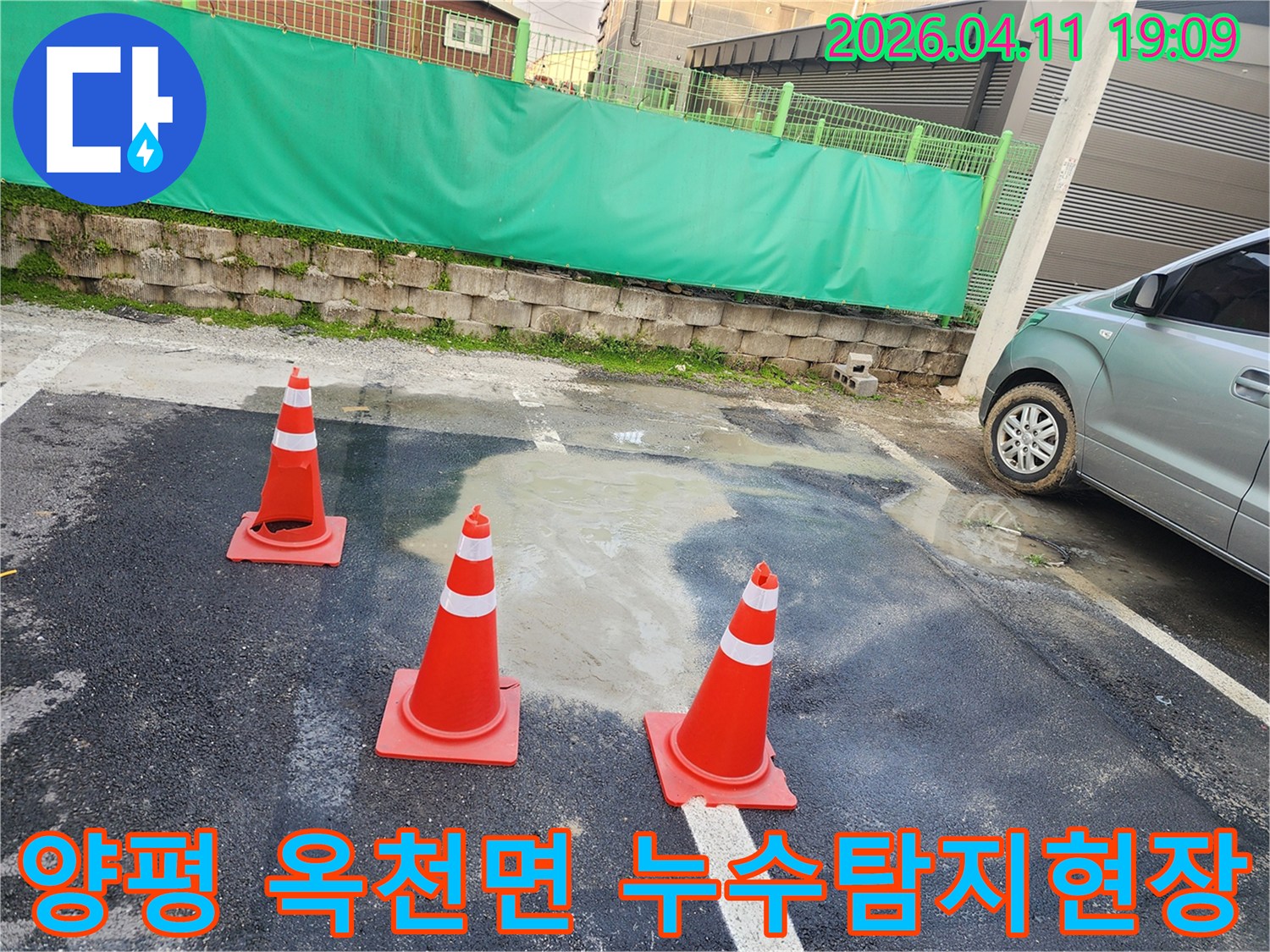 이 사진은 양평 옥천면의 누수 공사 현장에서-안전 확보를 위해 세워진 주황색 라바콘과-물이 고인 바닥을 보여주고 있습니다.