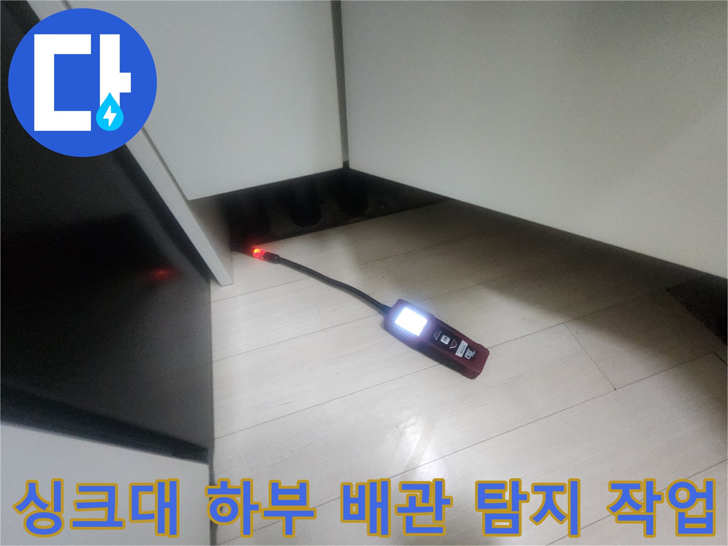 어두운 싱크대 밑 공간-가스 탐지기를 이용한 누수 포인트 확인 작업