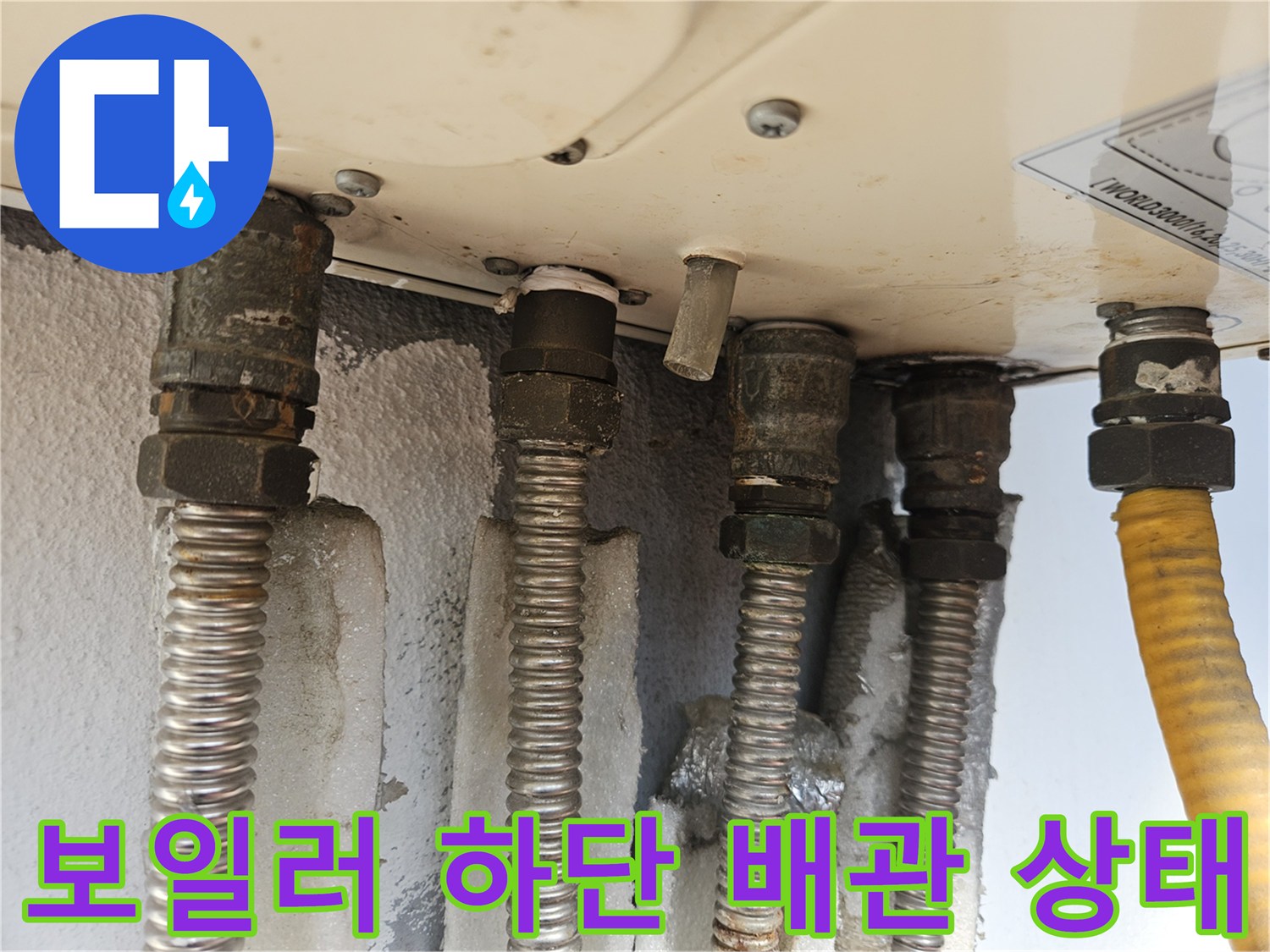 보일러 밑으로 연결된 여러 가닥의 배관과 호스들