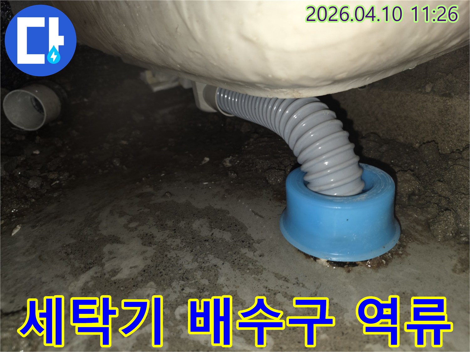 세탁기 배수 호스 아래 바닥에 물이 고여있는-배수구 역류로 인한 누수 현장 이미지