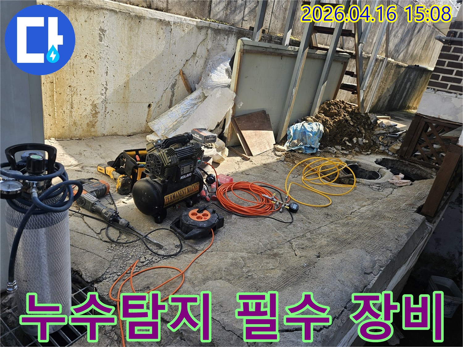 누수 공사 현장에서-에어 콤프레셔-함마드릴-호스-전선릴 등-다양한 전문 장비들이-콘크리트 바닥 위에-정돈된 채-작업 준비를 마친 모습