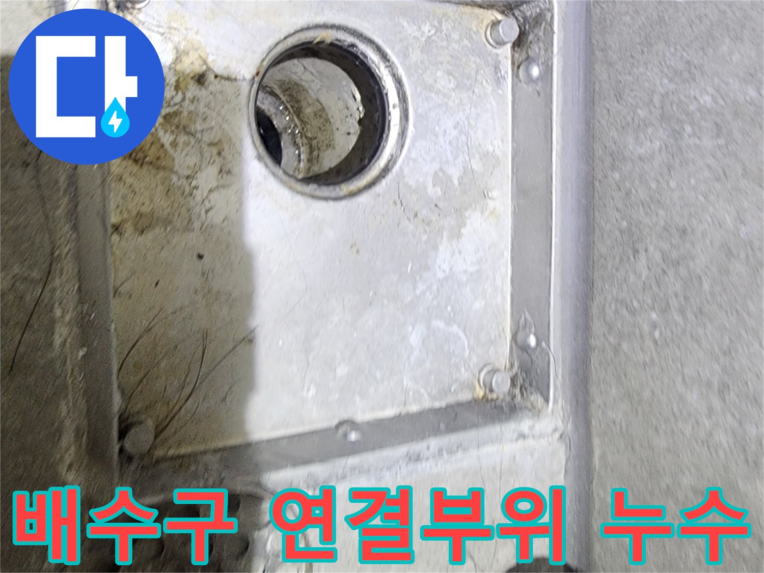 욕실 배수구의 내부 연결 부위와-주변의 오염 상태를-면밀히 관찰하며-누수 원인을-파악하고 있는 장면입니다