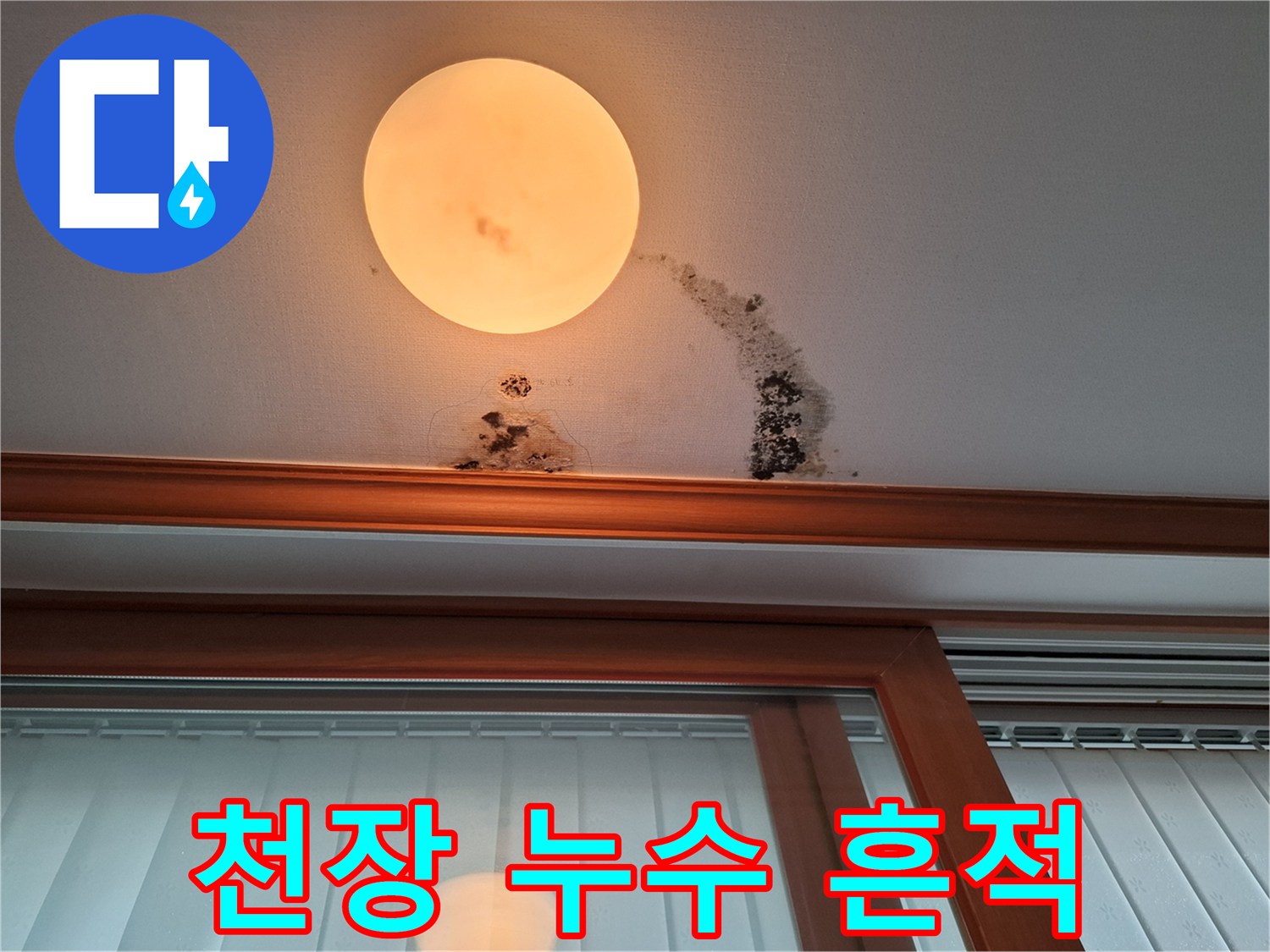 조명 아래 천장 벽지에 번진 갈색 누수 자국과 곰팡이 현상