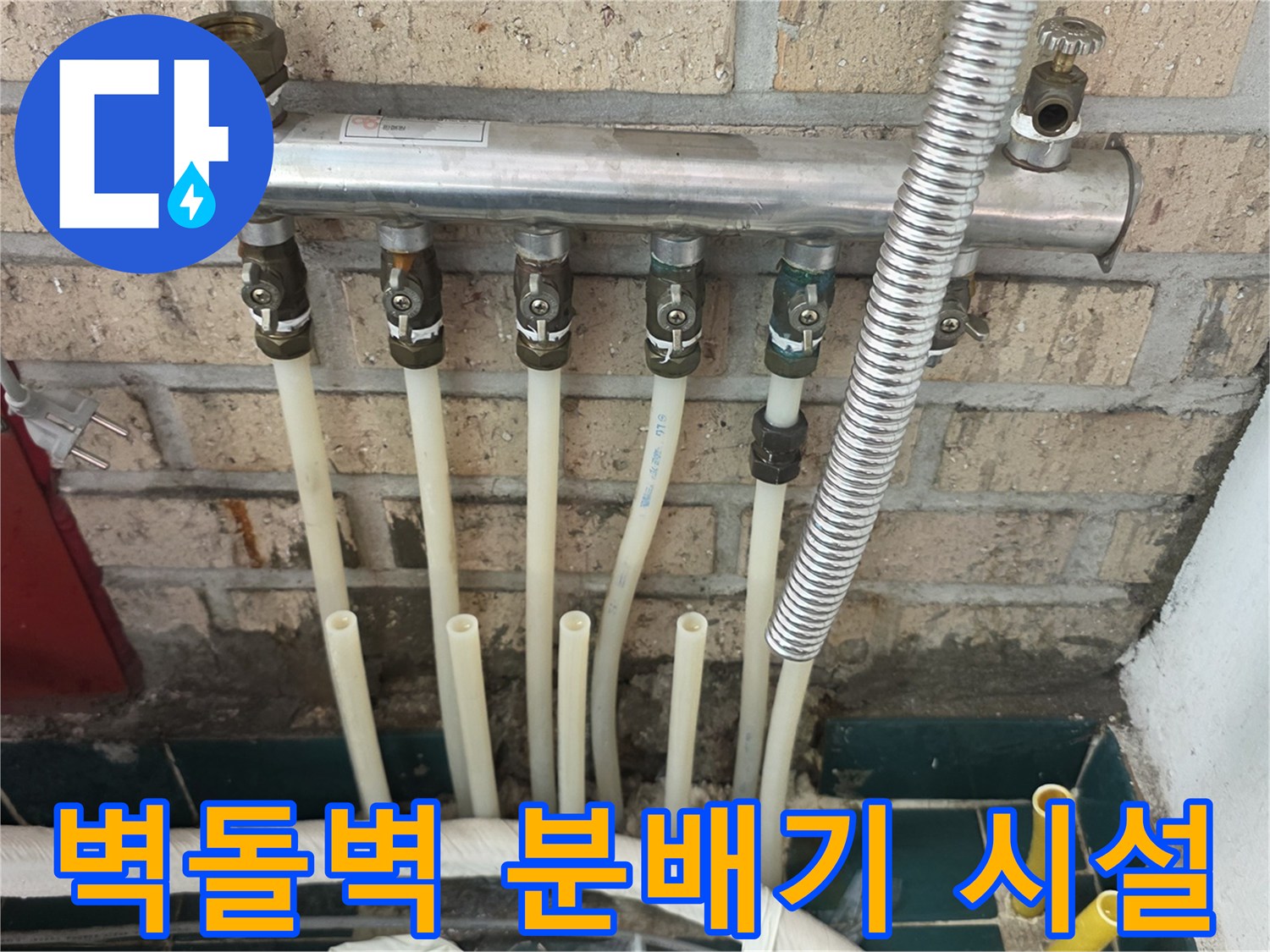 벽돌 벽에 설치된 금속 분배기와 연결된 여러 개의 배관