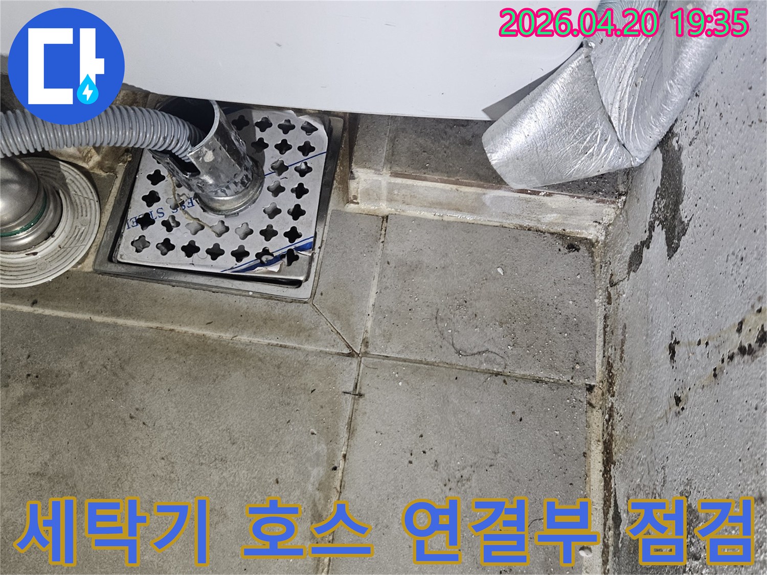 세탁기 배수 호스가-바닥 배수구에-연결된 모습으로-주변에 물때와-오염이 보이는-누수 현장 사진입니다.