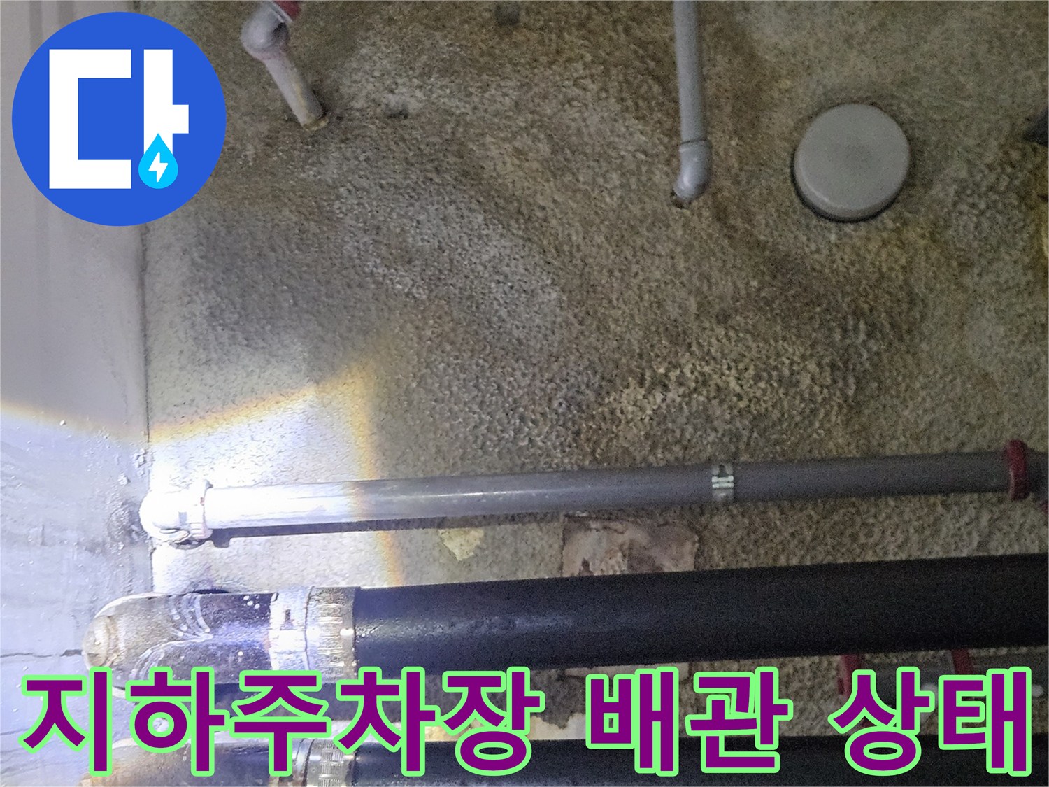 지하 주차장 천장에 설치된 검은색 및 회색 배관들의 모습입니다.