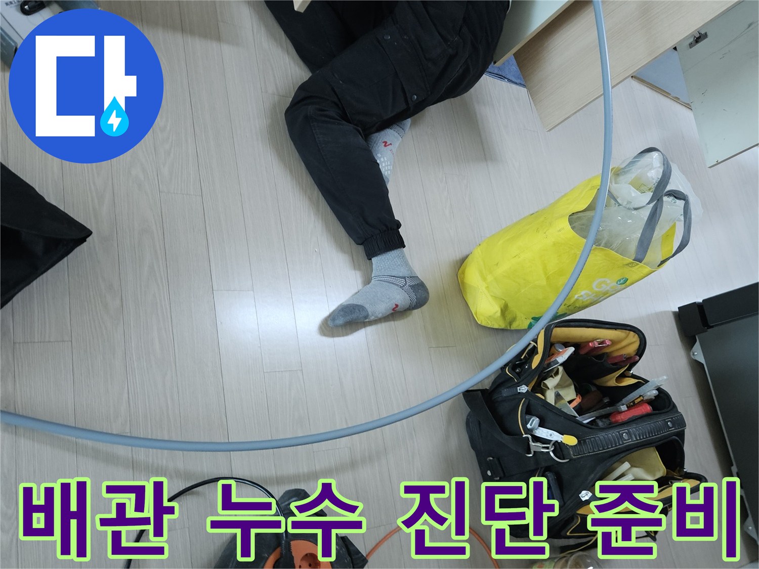 누수 탐지를 위해 싱크대 하부 공간에 장비를 배치하고 점검하는 장면