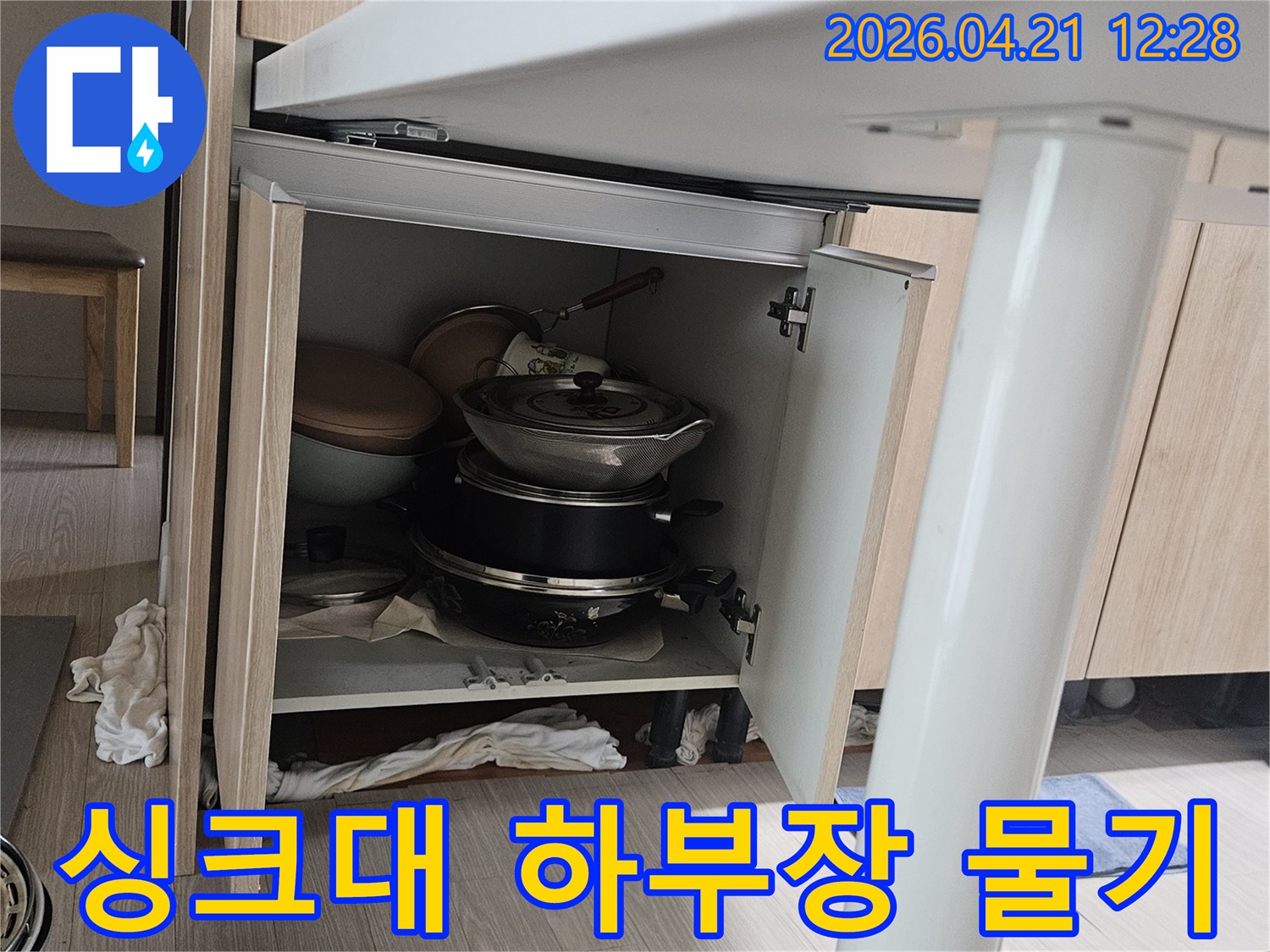싱크대 하부장 안쪽에서 발견된-물기로 인한 얼룩과 젖은 수납 공간-배관 문제로 인한 누수 현상