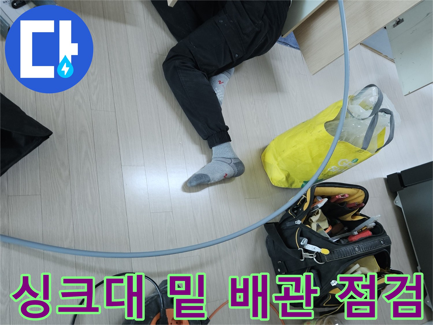 작업자가 싱크대 하단 공간에서 배관의 이상 유무를 확인하고 있습니다.