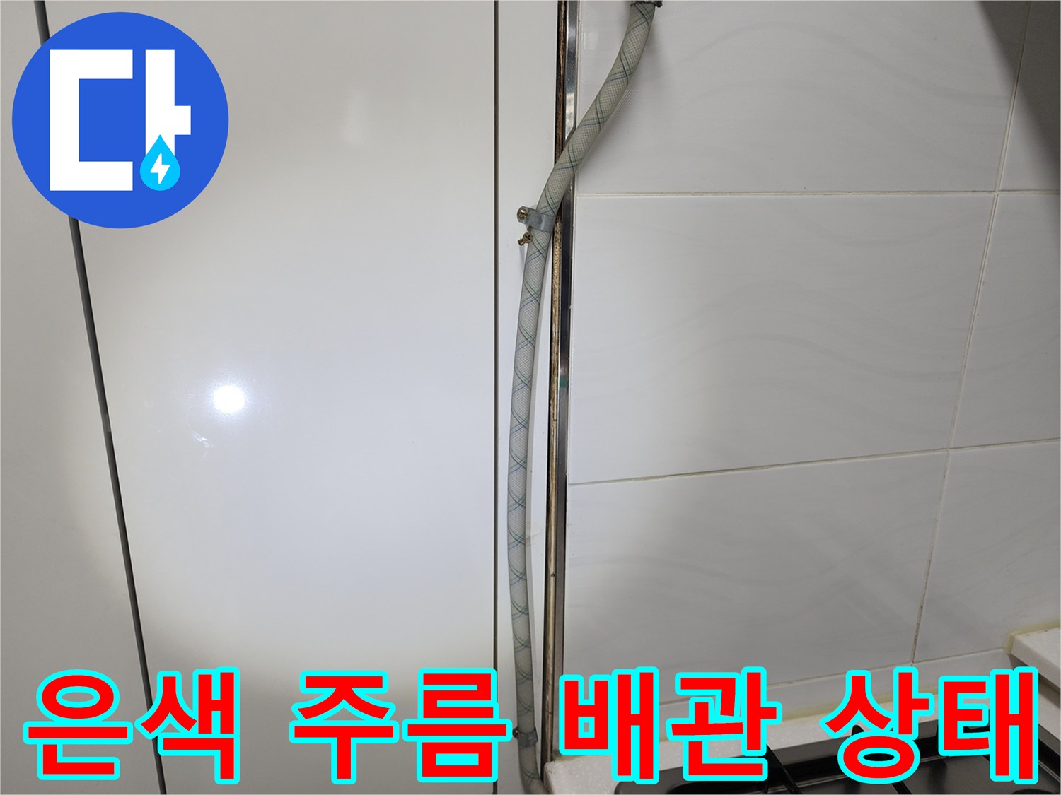 하얀 타일 벽면에 설치된 수도용 주름관 연결 부위
