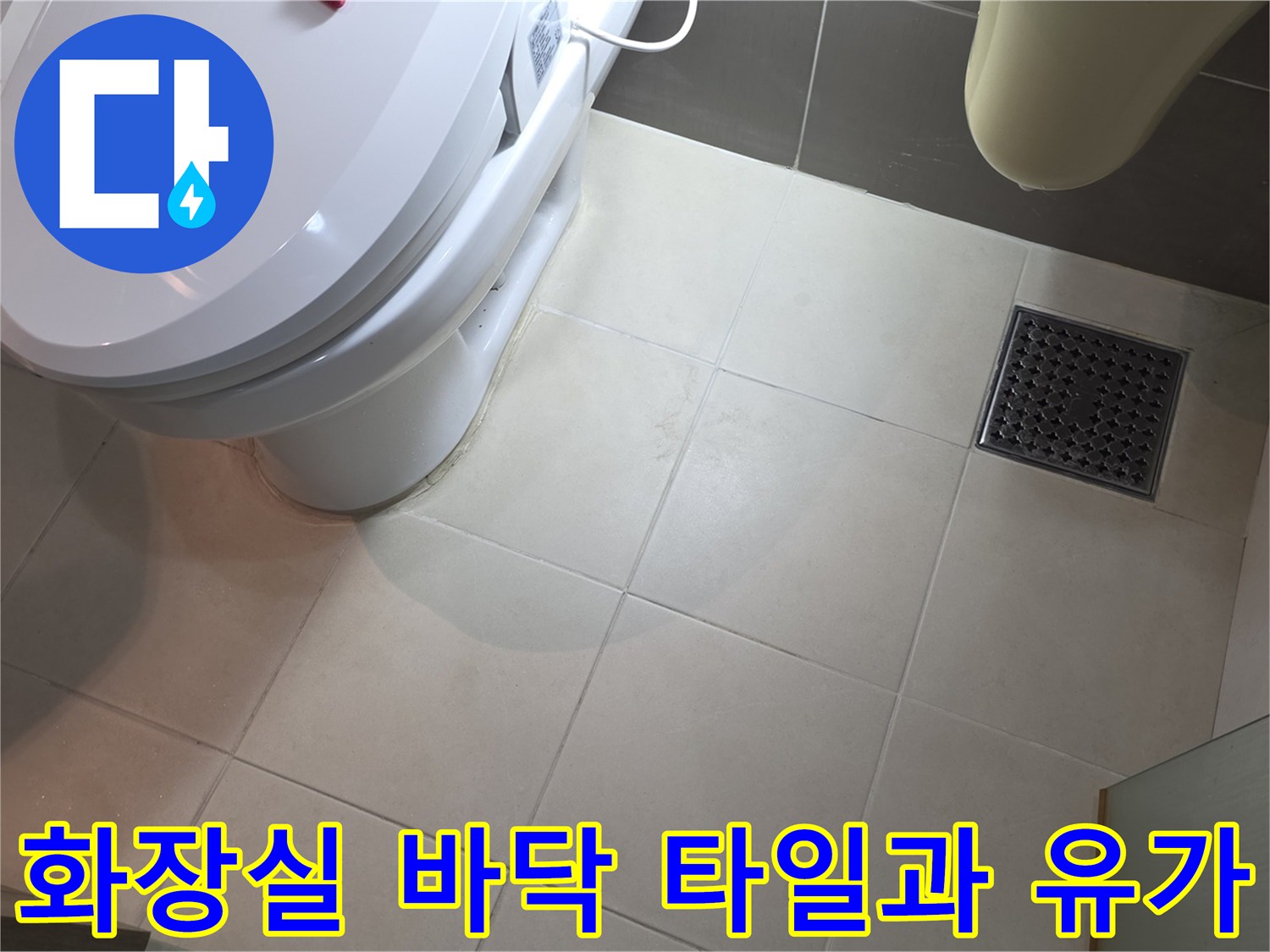 변기 옆 배수구 주변의 타일 마감 상태를 찍은 사진입니다.