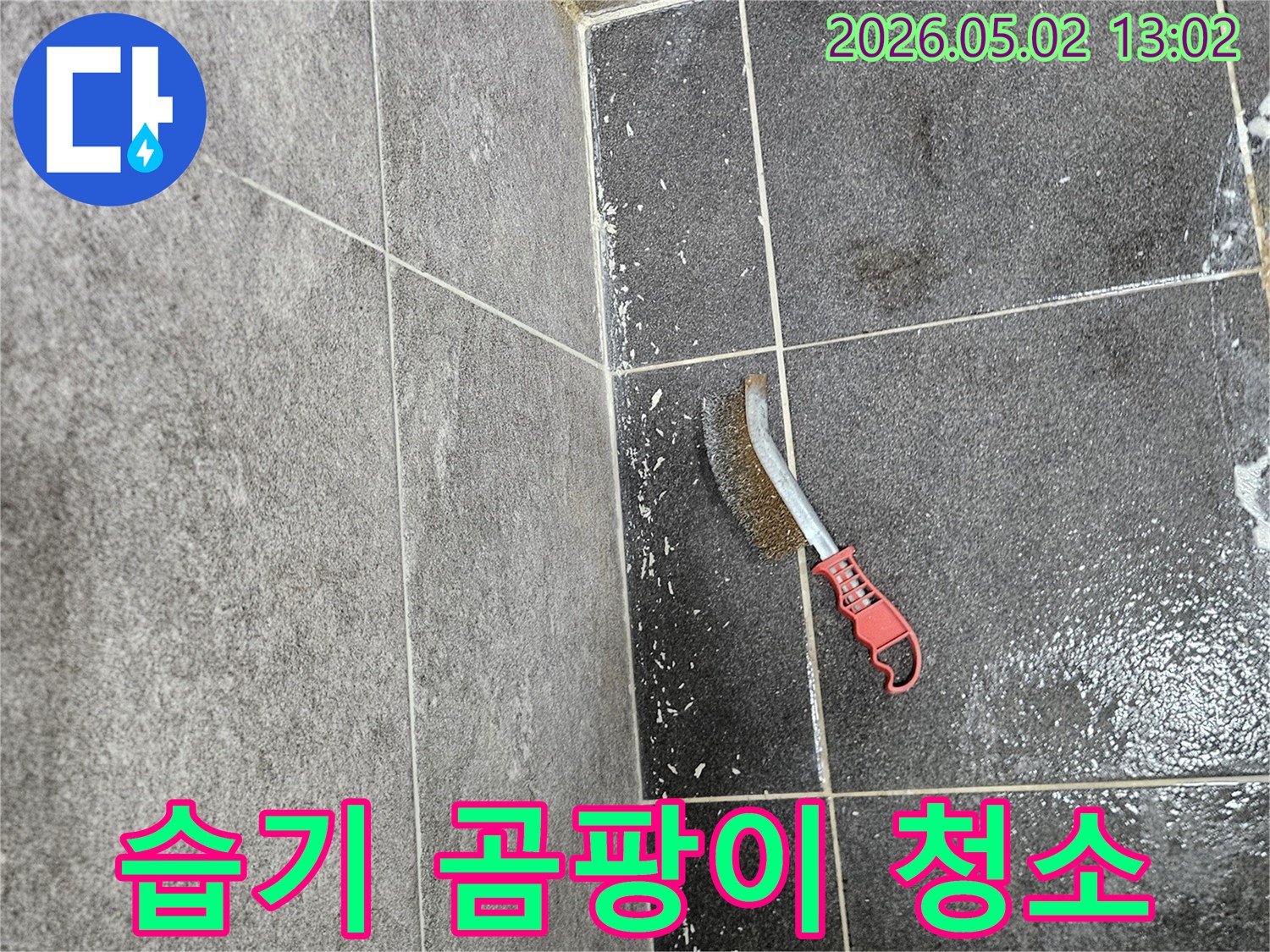 누수로 인해 습해진 타일 바닥의 곰팡이를-제거하기 위해-와이어 브러시가 사용되는 모습