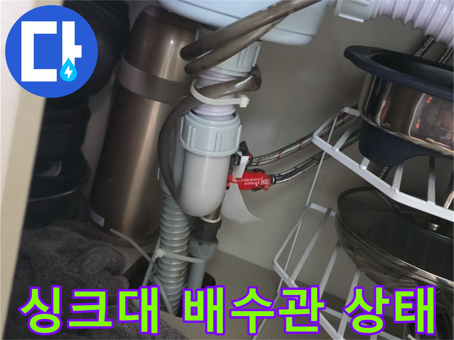 주방 싱크대 하부장 내부의 배수 호스와 연결 부위 모습입니다.
