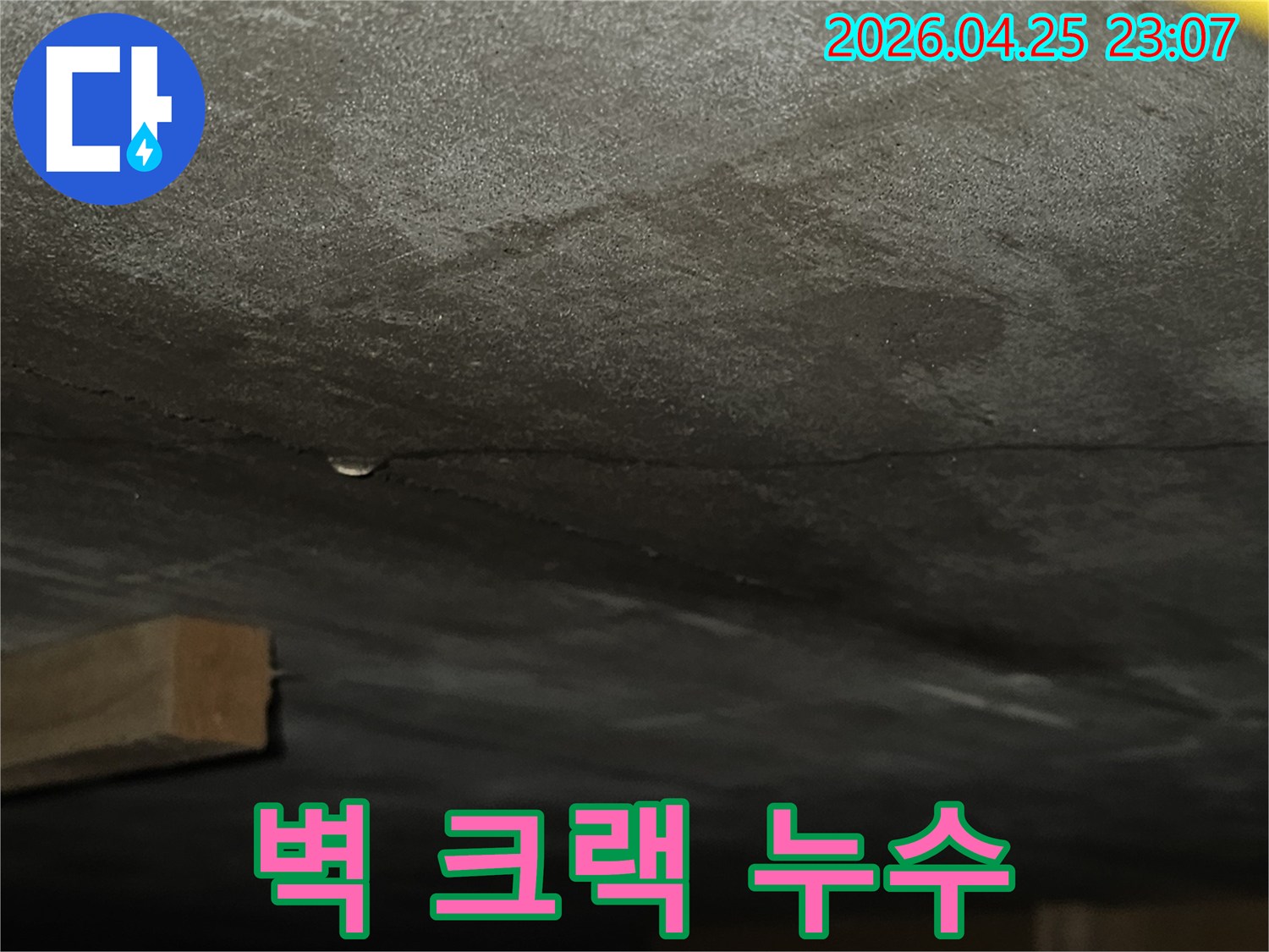 벽면의 갈라진 틈 사이로 물기가 스며들어 어둡게 변색된-누수 현장을 보여주는 클로즈업 사진
