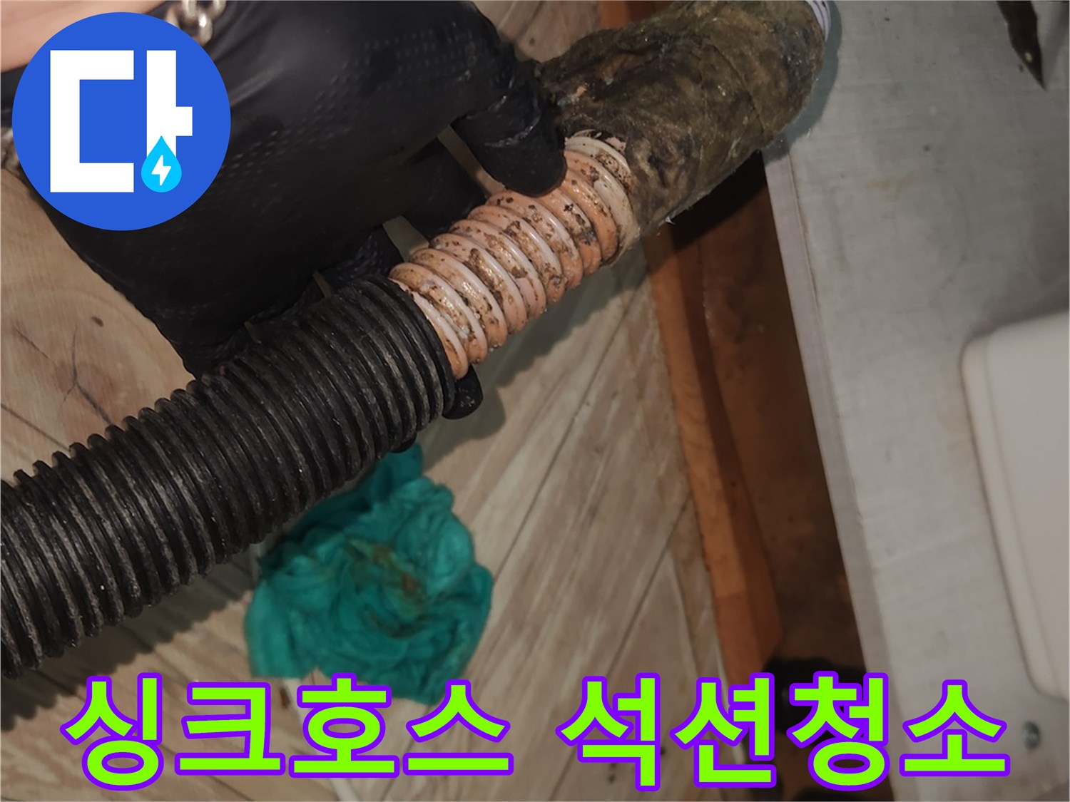 검은 장갑을 낀 손이-심하게 오염된 싱크대 배수 호스를-석션 클리닝하기 위해-잡고 있는 모습