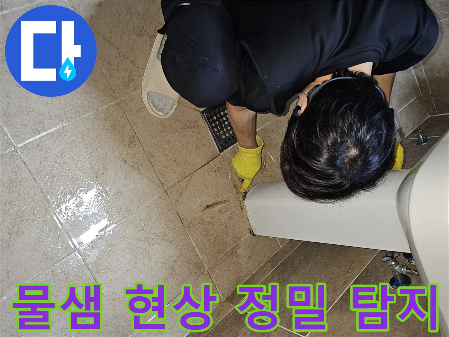 전문 엔지니어가-노란 장갑을 끼고-욕실 바닥의 젖은 타일과-세면대 하단부를-집중적으로 관찰하며-누수 지점을 정밀하게 탐지하고 있습니다