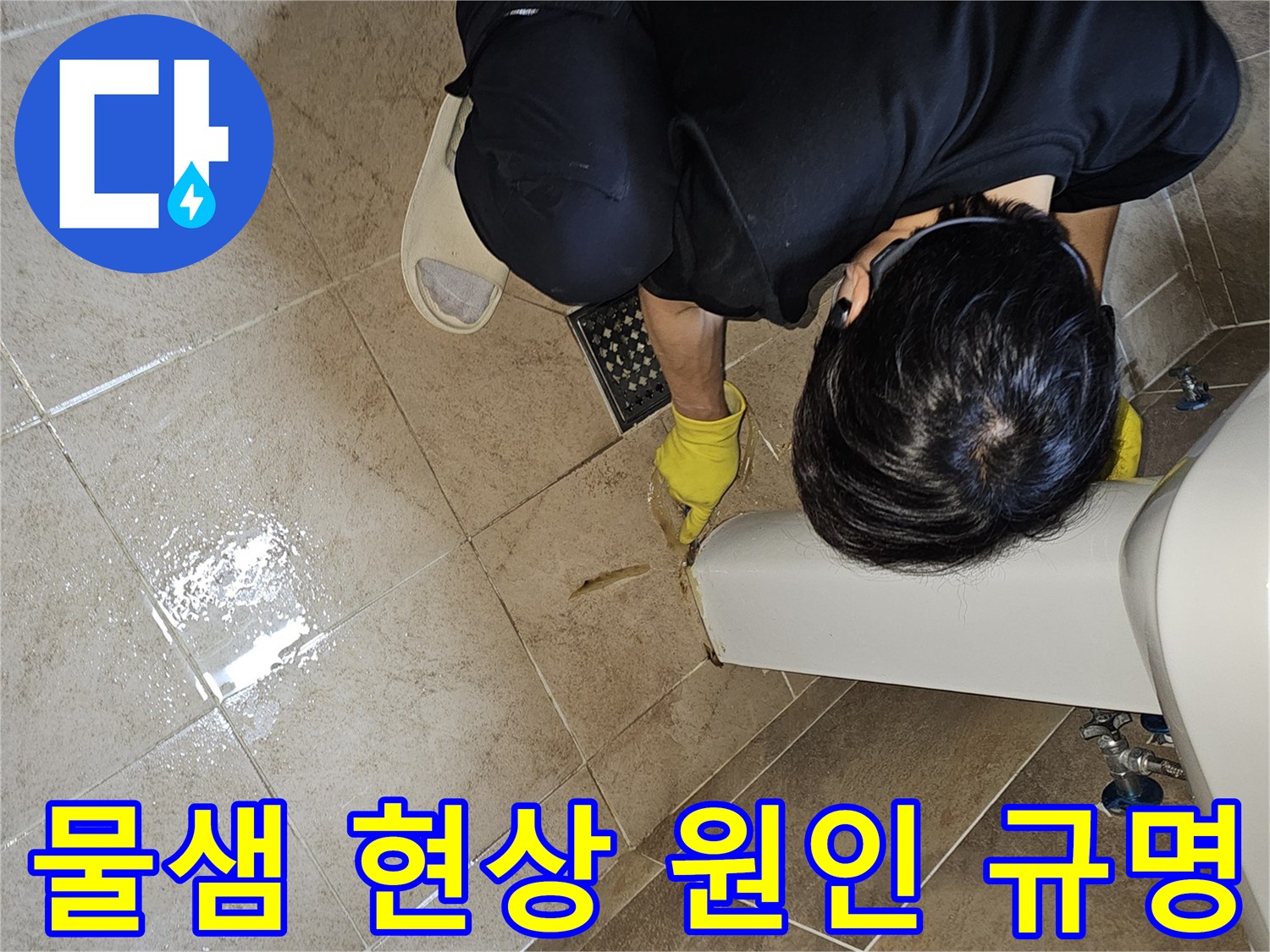 전문 엔지니어가-노란 장갑을 끼고-욕실 바닥의 젖은 타일과-세면대 하단부를-집중적으로 관찰하며-누수 지점을 정확하게 규명하고 있습니다