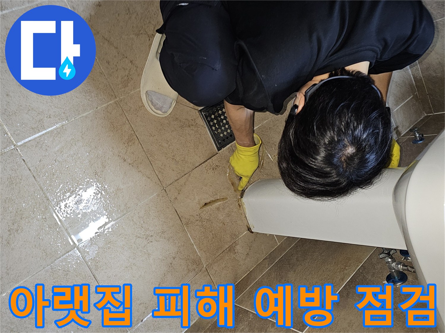 전문 엔지니어가-노란 장갑을 끼고-욕실 바닥의 젖은 타일과-세면대 하단부를-집중적으로 관찰하며-아랫집 피해 예방을 위한-누수 지점을 파악하고 있습니다