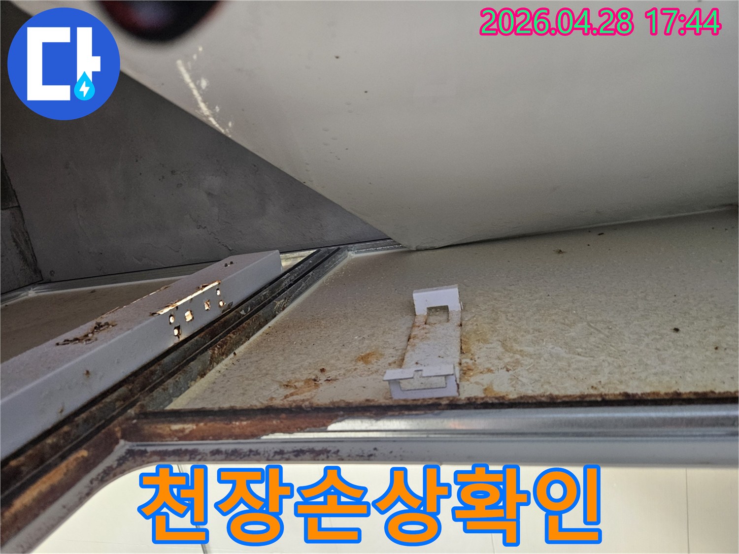 아래층 욕실 천장에서 발견된 심각한 누수 흔적을 보여주는 사진입니다-녹슨 금속 구조물과 변색된 천장 마감재가 명확하게 보입니다.