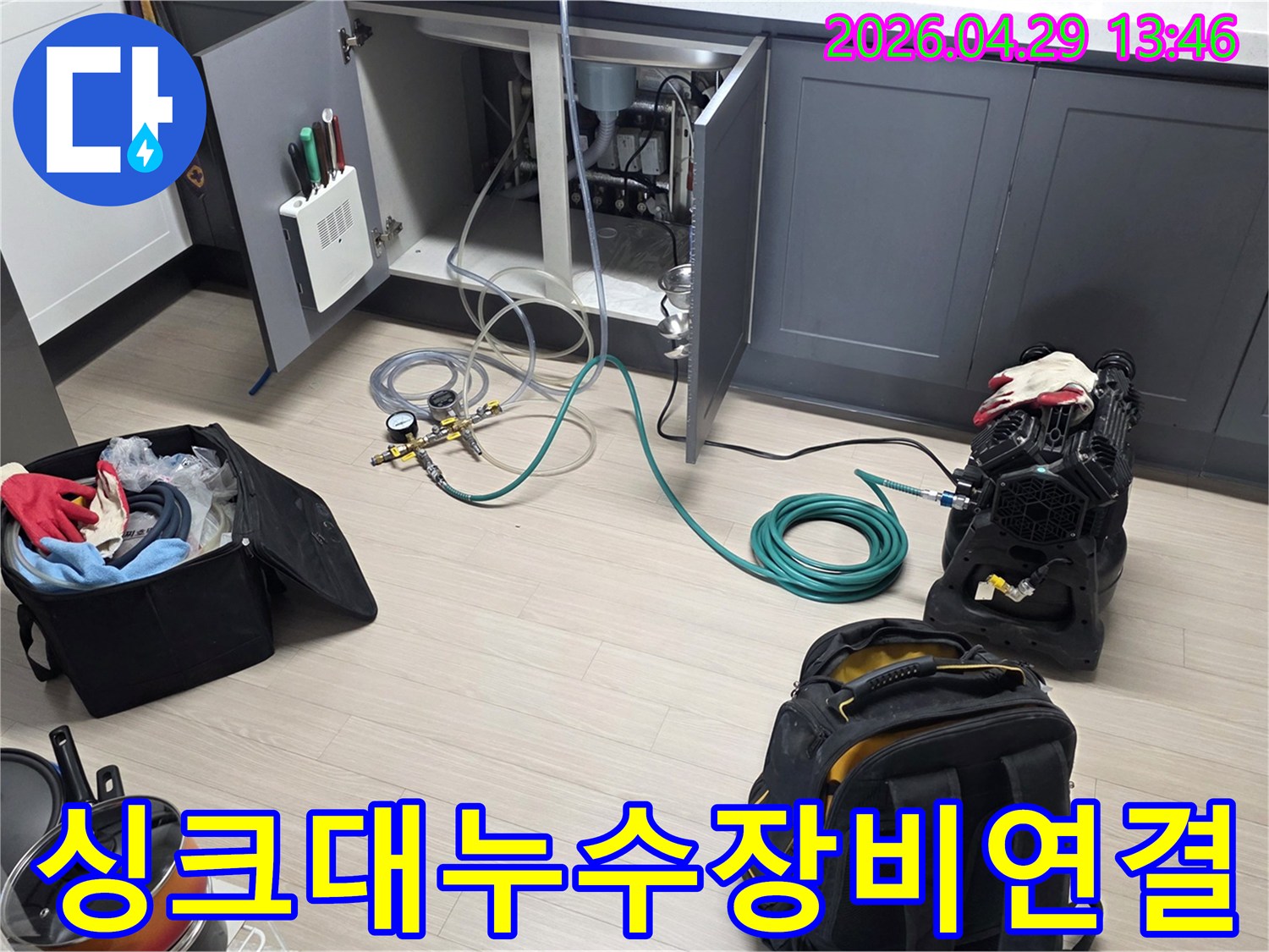 싱크대 하부장 내부에서-누수 탐지를 위한-압력 게이지와-호스를 연결하고-공기 압축 장비를-설치하는 모습입니다