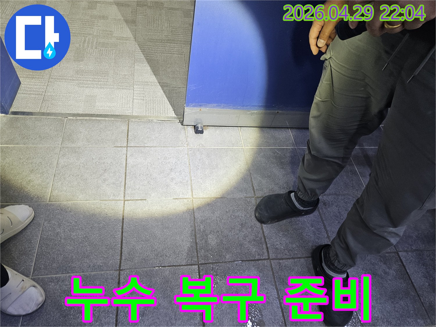 누수 전문가가 바닥에 고인 물기를 확인하며-누수 복구 작업을 위한 초기 현장 조사를 하고 있습니다.