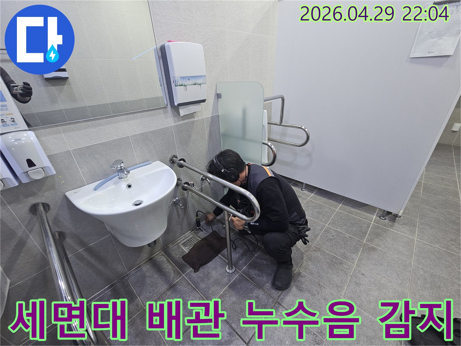 누수 전문가가-청음식 탐지기로-화장실 세면대 하부 배관에서-누수음을 정밀하게 감지하는 모습