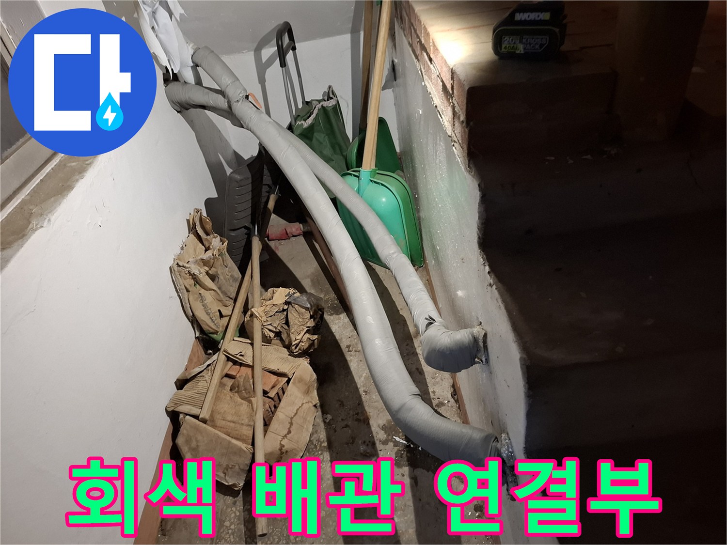 벽면-옆에-놓여있는-배관과-작업용-삽-및-자재들