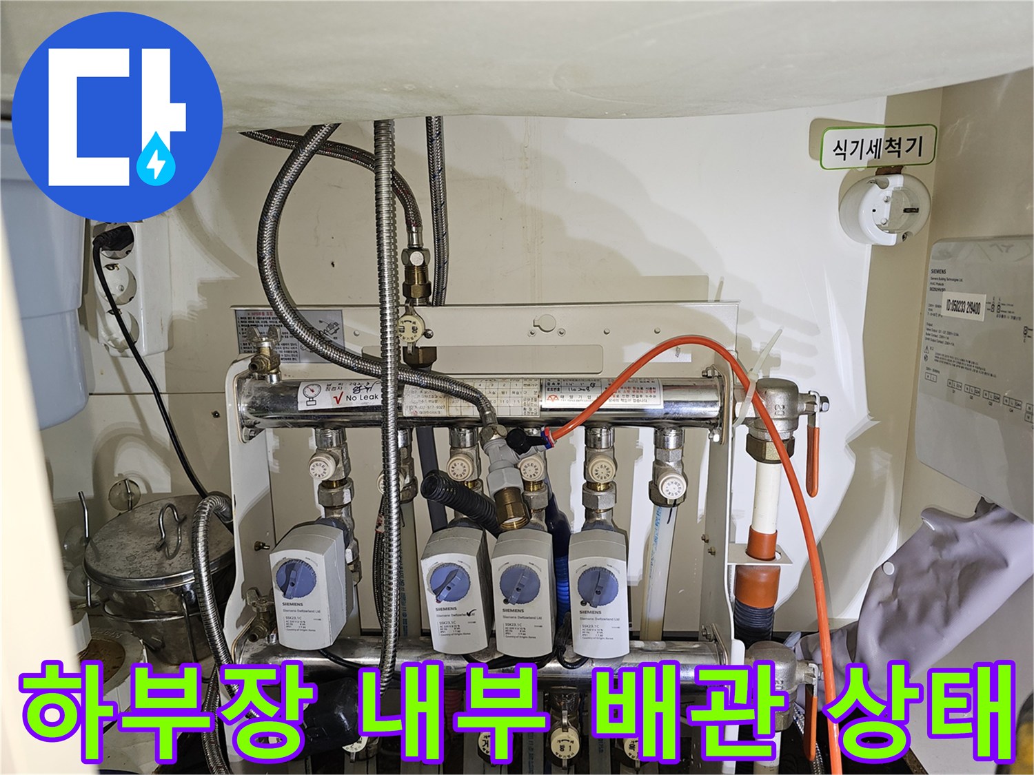 싱크대-하부장-안쪽-복잡한-난방-분배기-및-연결-호스-점검-사진