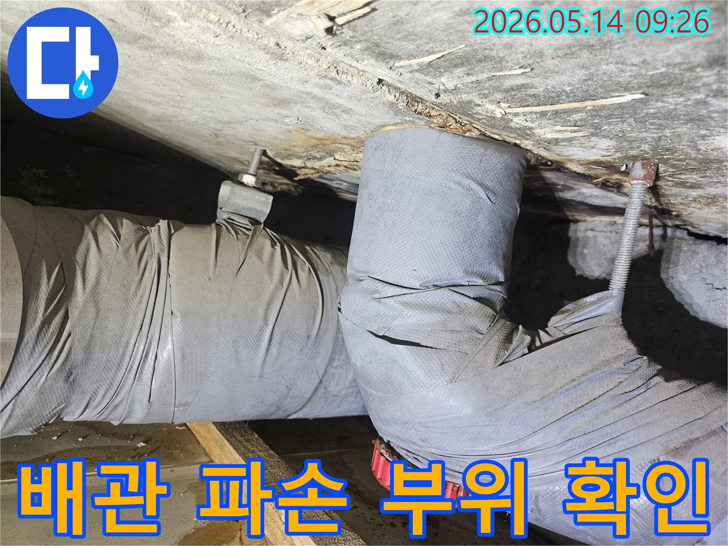 천장 배관의 파손 부위에서 물이 새어-단열재가 젖고 주변이 오염된-누수 현장을 보여줍니다